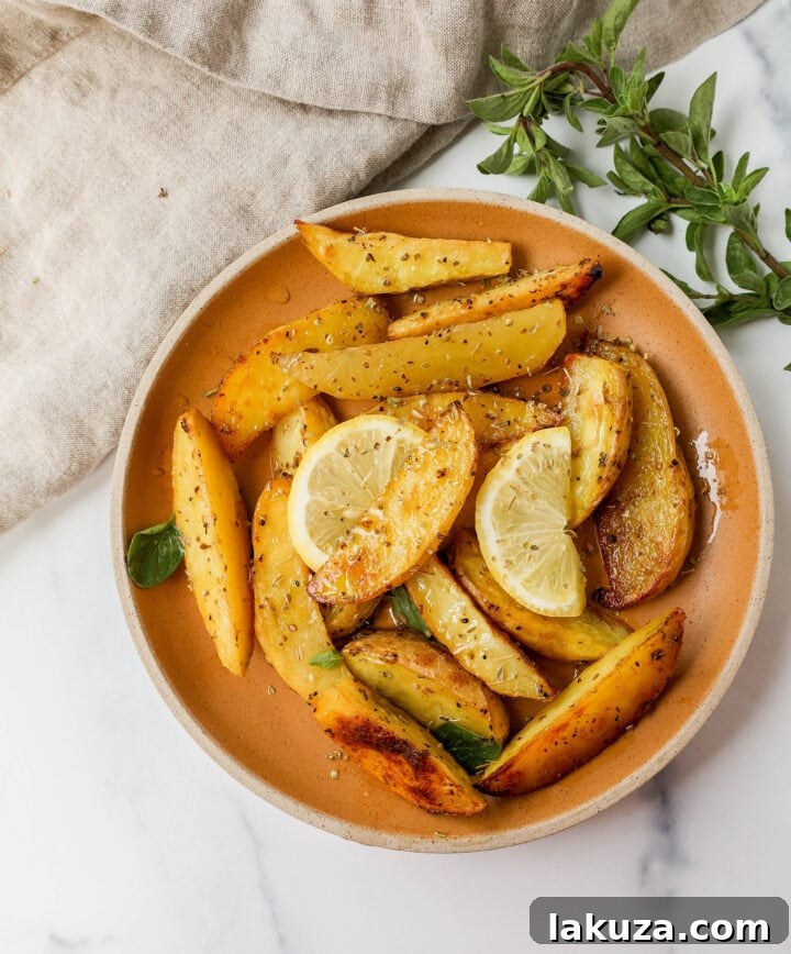 These Greek Roasted Potatoes are infused with extra-virgin olive oil, lemon juice, garlic, oregano, spices, and chicken broth which makes the creamiest roasted potatoes full of Greek flavor.
