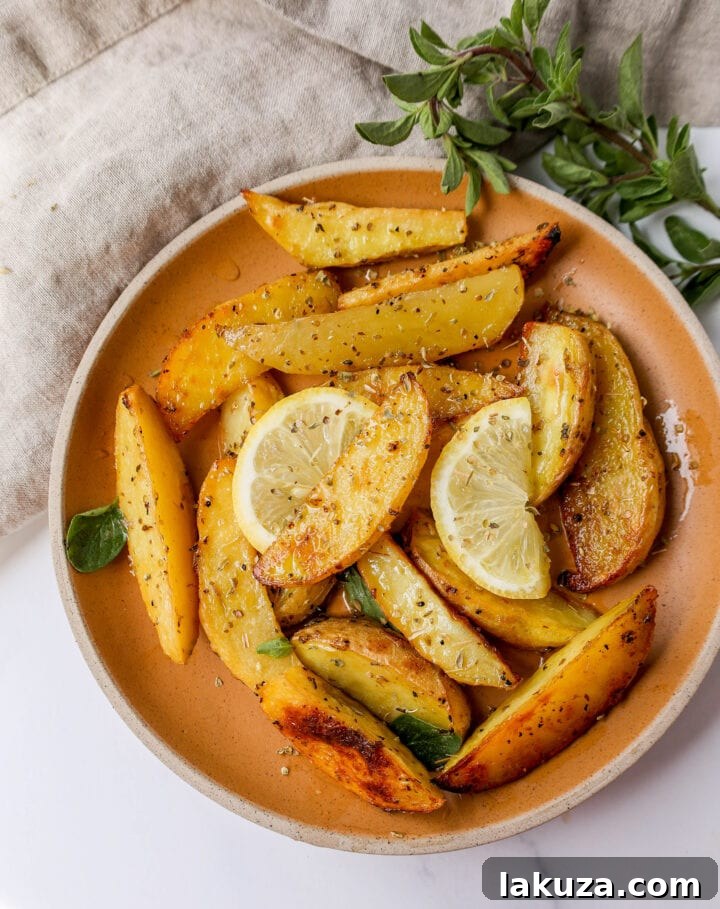 These Greek Roasted Potatoes are infused with extra-virgin olive oil, lemon juice, garlic, oregano, spices, and chicken broth which makes the creamiest roasted potatoes full of Greek flavor.