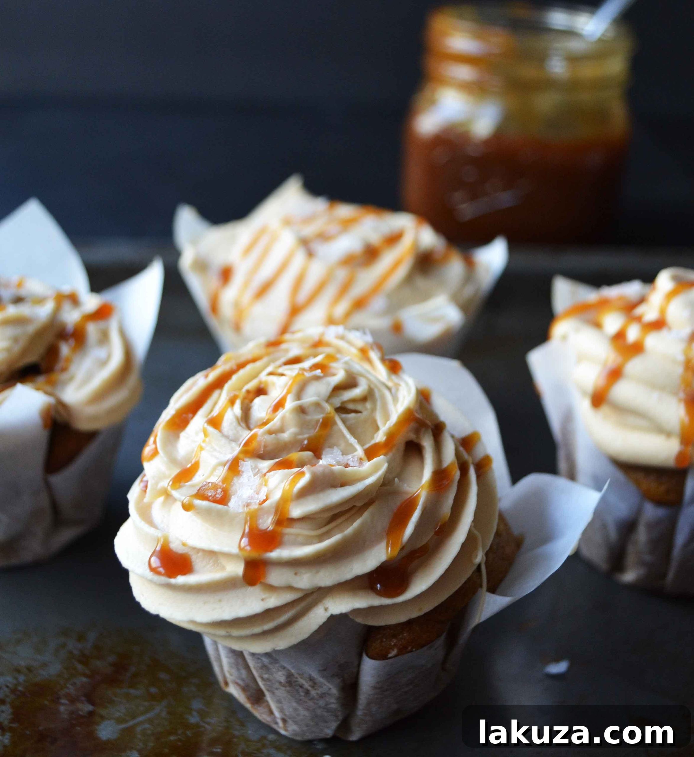Up-close view of a perfectly baked cinnamon-spiced pumpkin cupcake, generously topped with a swirl of homemade salted caramel frosting, highlighting its tempting texture.