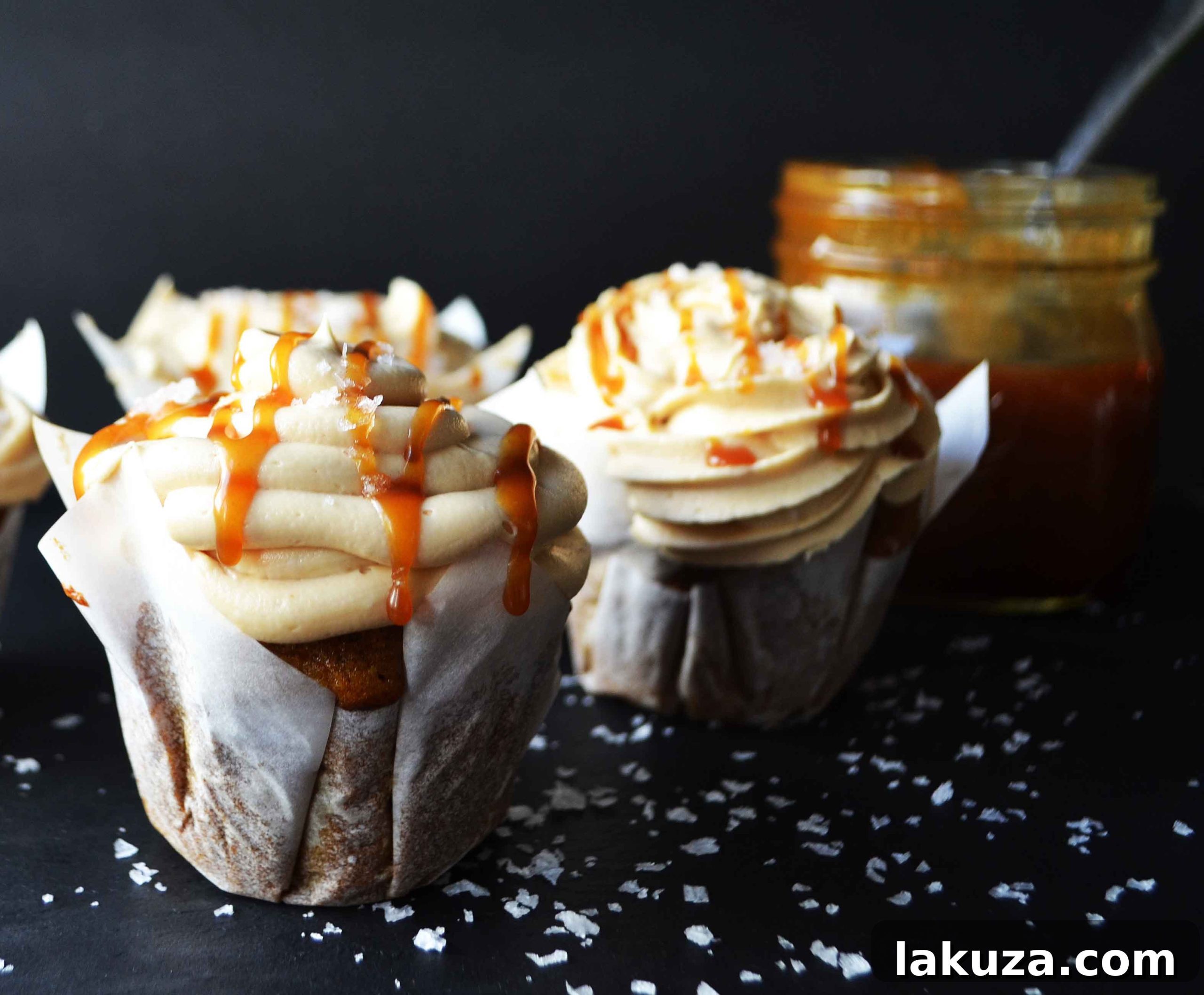 A close-up of a pumpkin cupcake with a swirl of light and fluffy salted caramel frosting, showcasing its inviting texture.
