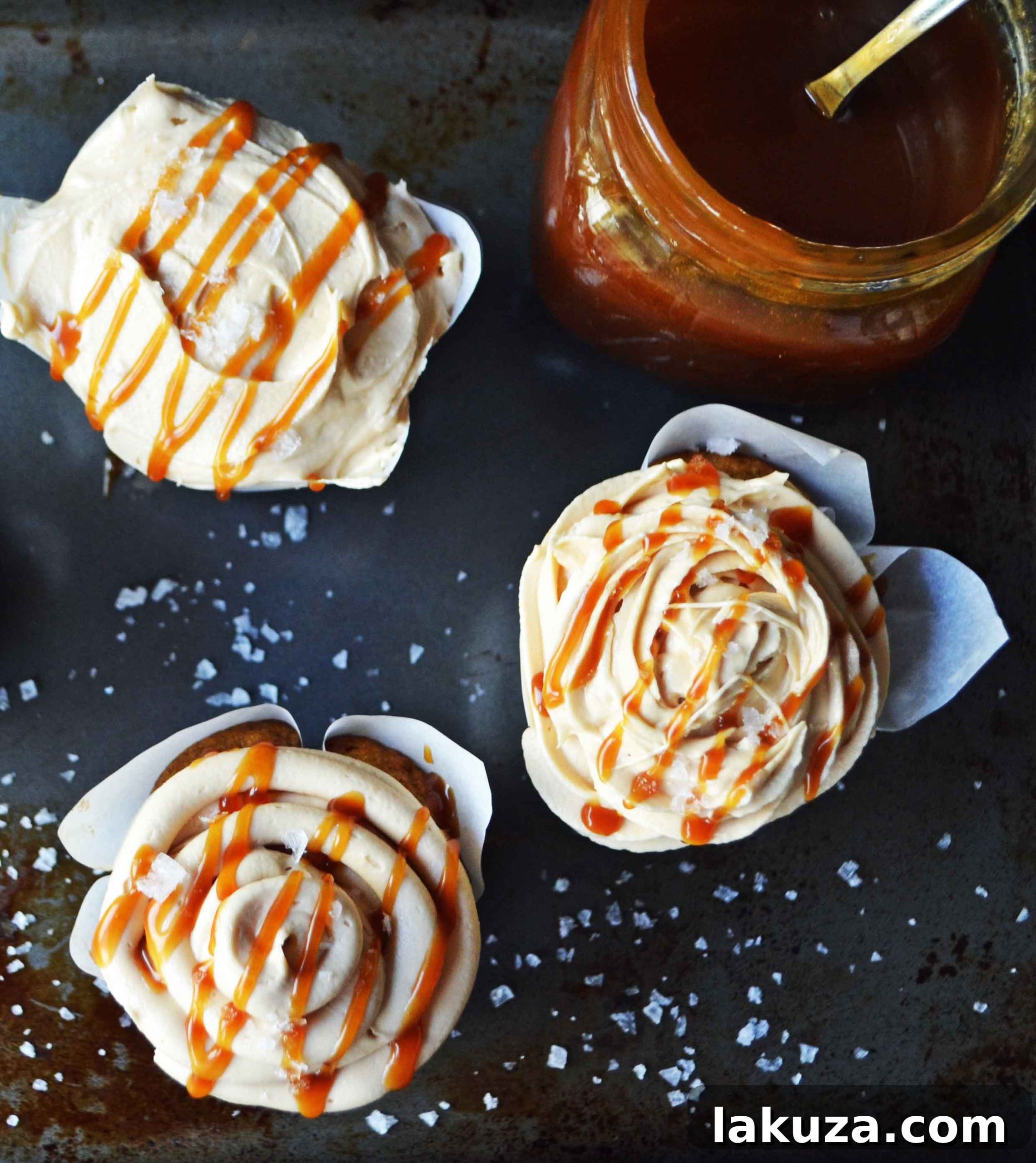 A trio of freshly baked pumpkin cupcakes, beautifully adorned with golden-brown salted caramel frosting, ready for a fall celebration.