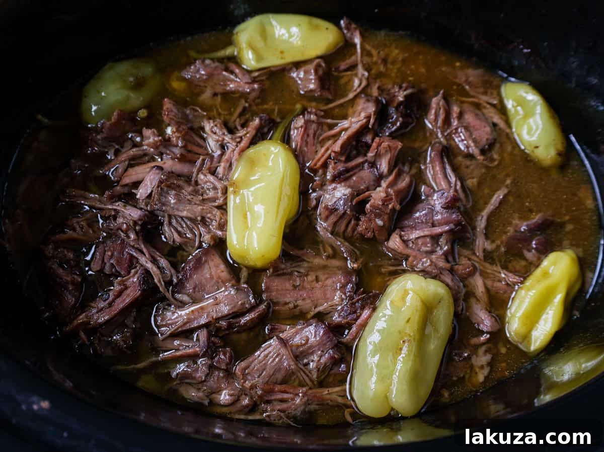 Pepperoncinis and butter added on top of the seasoned chuck roast in the slow cooker.