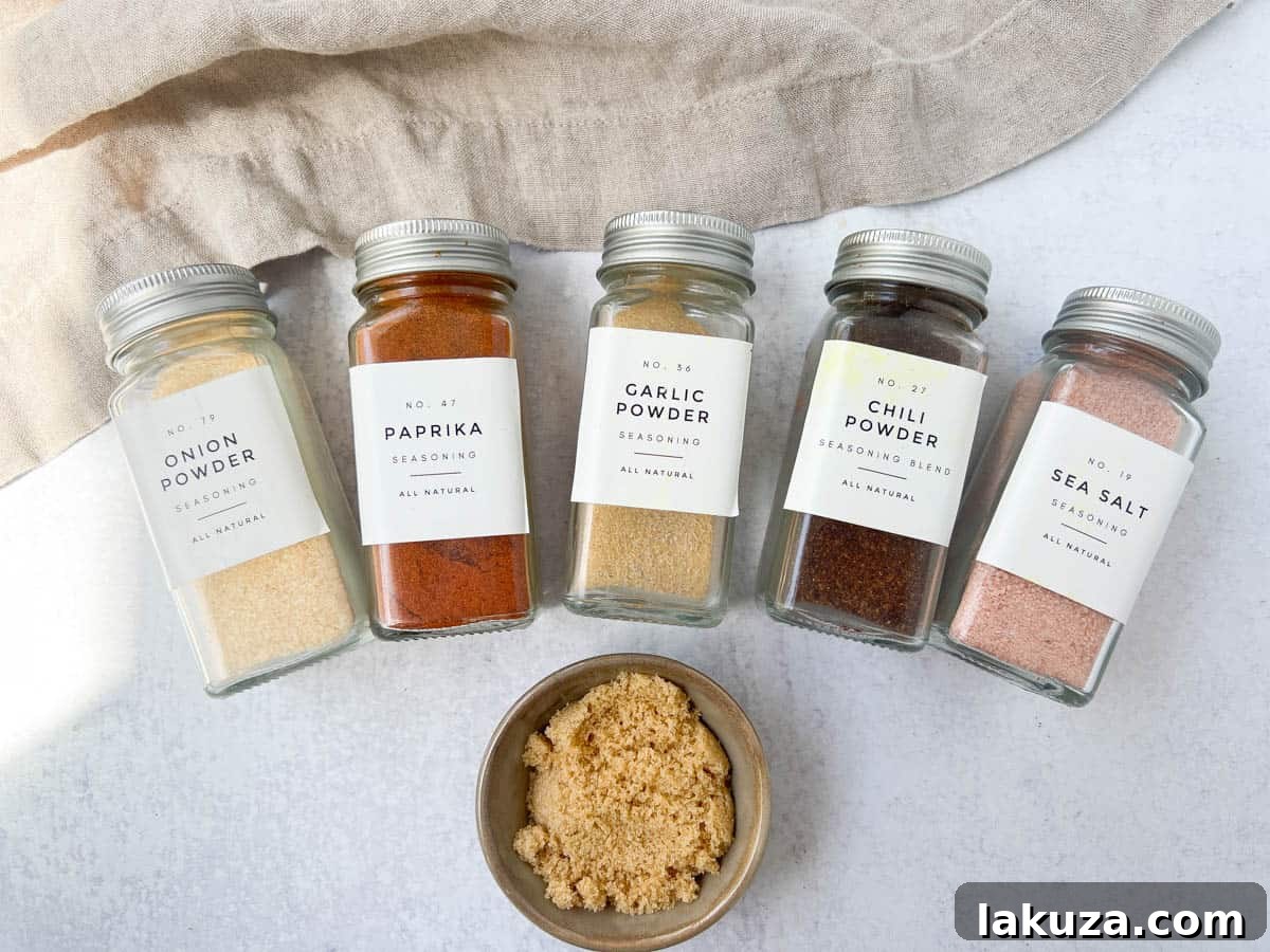 A selection of spices for the homemade chicken rub, including salt, garlic powder, onion powder, paprika, chili powder, and brown sugar.
