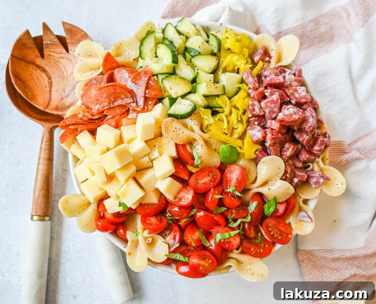 Zesty Italian Pasta Medley 2 A large, colorful bowl of Italian Pasta Salad, featuring perfectly cooked pasta, chunks of salami and pepperoni, cubes of provolone cheese, vibrant grape tomatoes, sliced cucumbers, and a scattering of pepperoncini peppers, all glistening with a creamy red wine vinaigrette.