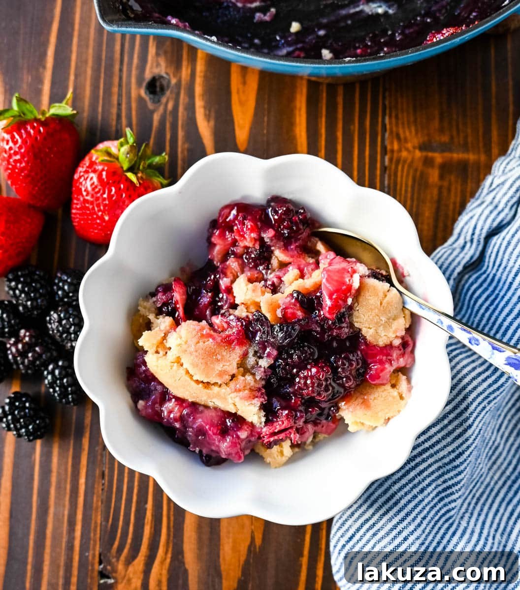 A close-up of a homemade berry crisp, showcasing the vibrant fresh berries and the golden-brown, buttery sugar cookie crumble topping, served in a rustic dish.