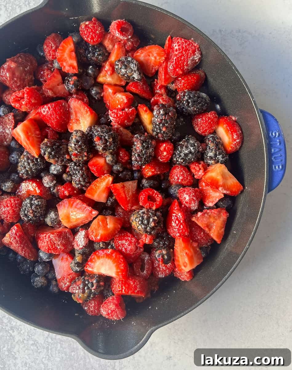 A close-up of the homemade Mixed Berry Crisp, revealing the juicy, cooked berries and the golden, textured crumble topping, perfect for a summer dessert.