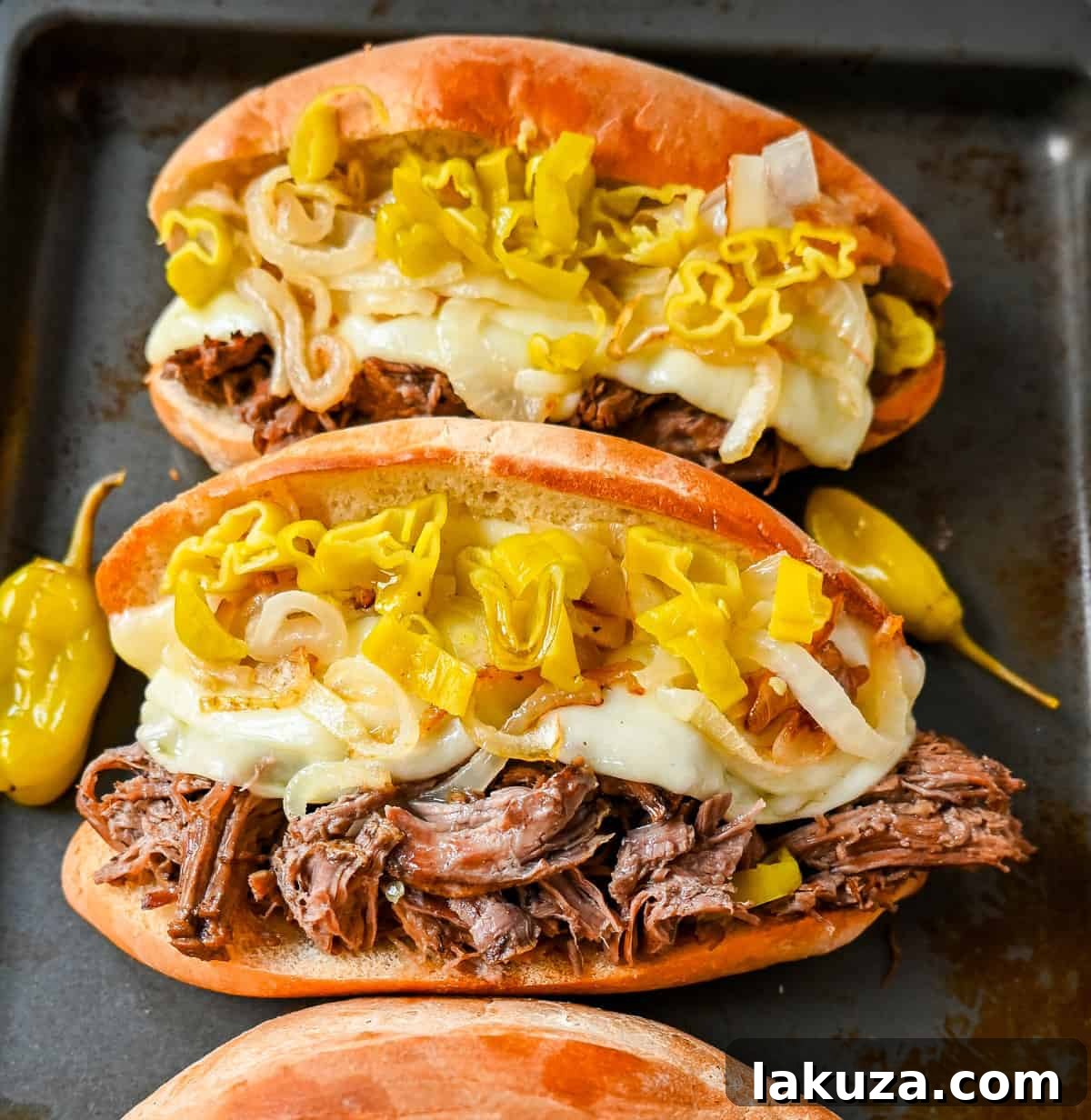 Mouthwatering Slow Cooker Italian Beef Sandwiches with provolone, caramelized onions, and pepperoncinis, ready to serve.