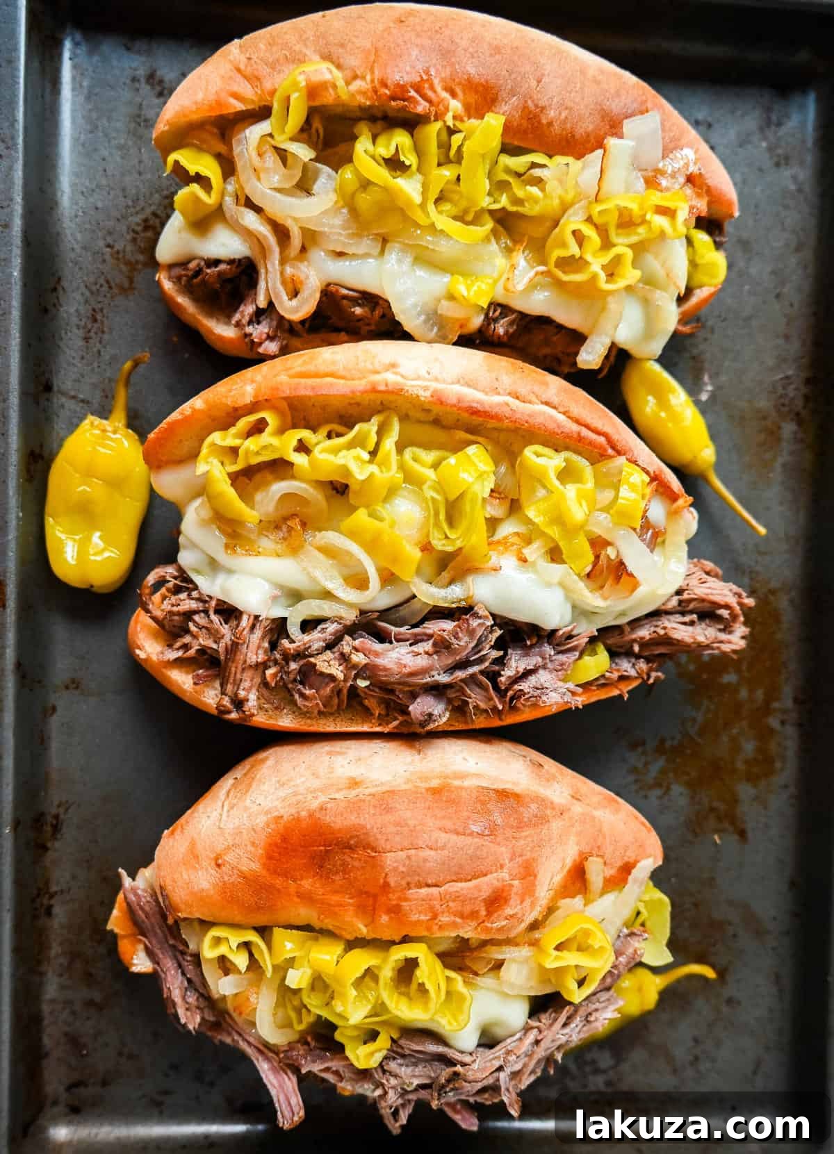 Close-up of a perfectly constructed Italian Beef Sandwich with shredded beef, cheese, onions, and peppers on a toasted bun.