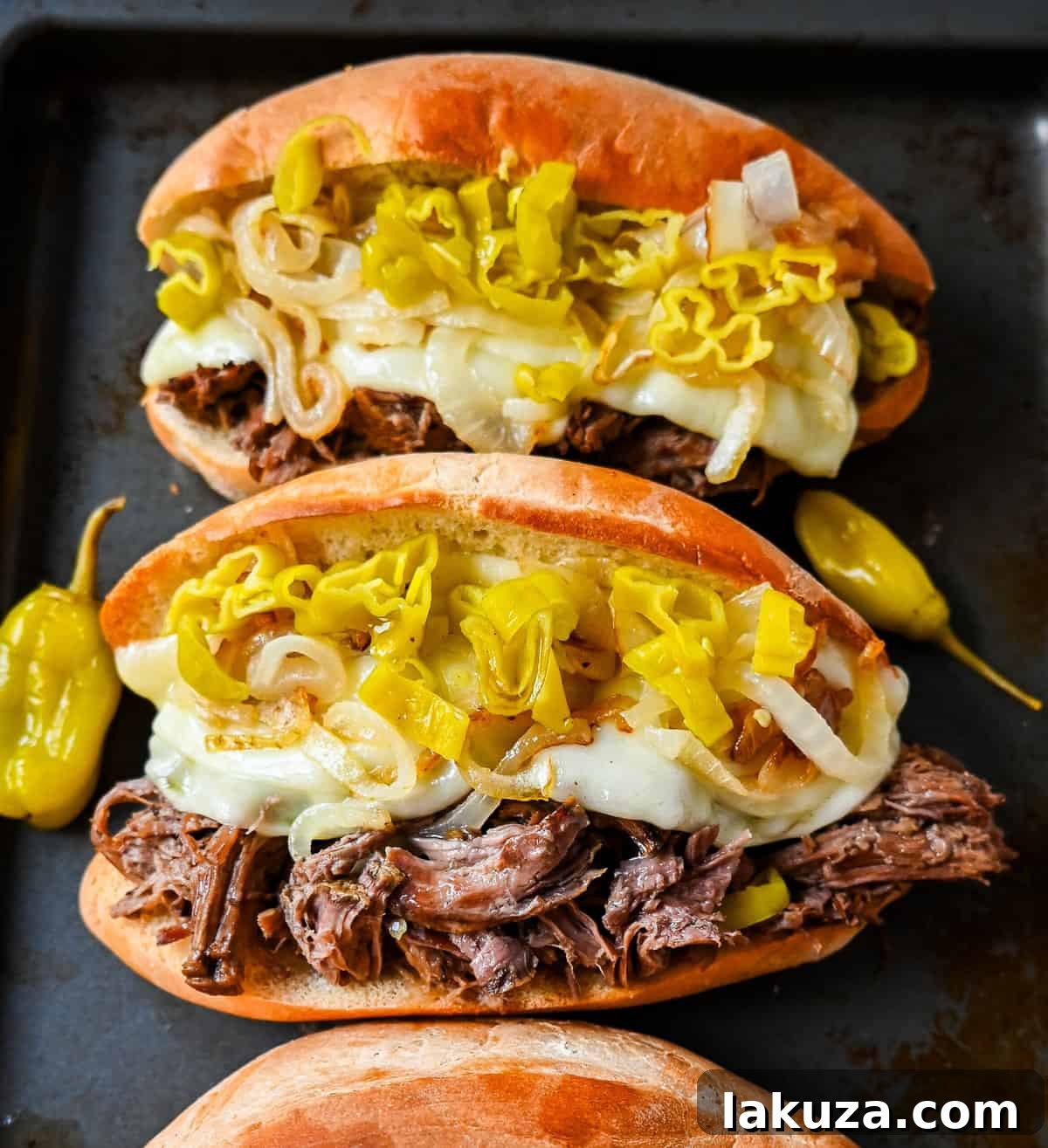 Finished Slow Cooker Italian Beef Sandwiches arranged on a platter, showcasing the melted provolone and caramelized onions.