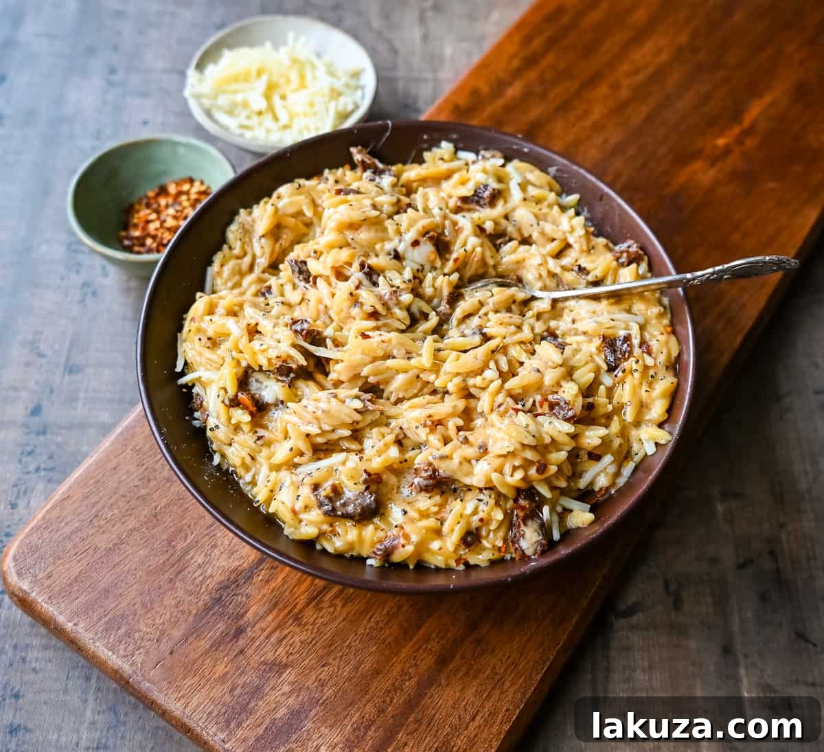 A large skillet filled with creamy Boursin Cheese Sundried Tomato Orzo, ready to be served. The rich sauce and vibrant sundried tomatoes are clearly visible.