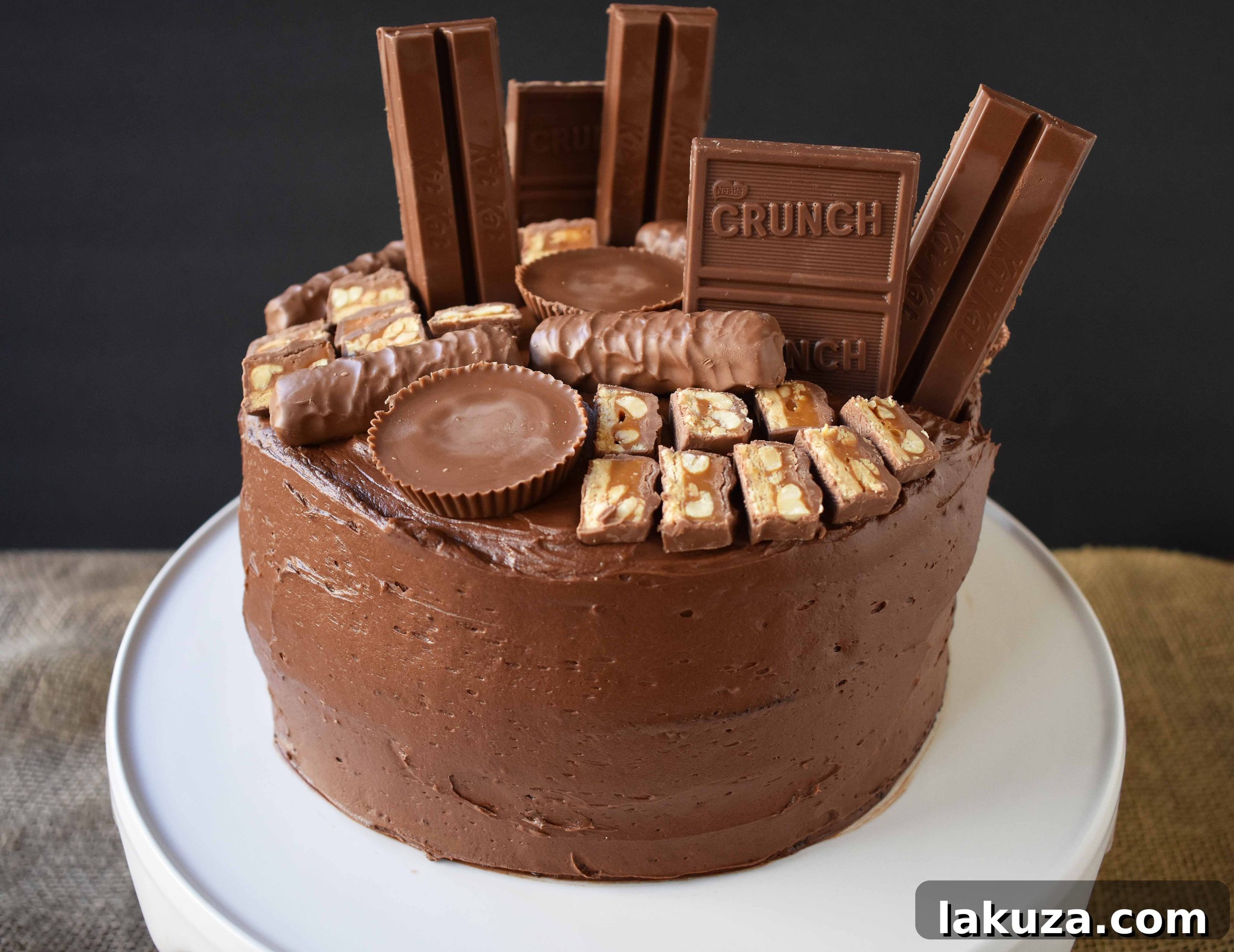 Indulge in the ultimate Chocolate Candy Bar Cake, a decadent five-star rated dessert featuring a moist chocolate cake, silky chocolate buttercream, and a generous topping of assorted chocolate candy bars. Perfect for birthdays, Halloween, or any chocolate craving. Visit modernhoney.com for more.