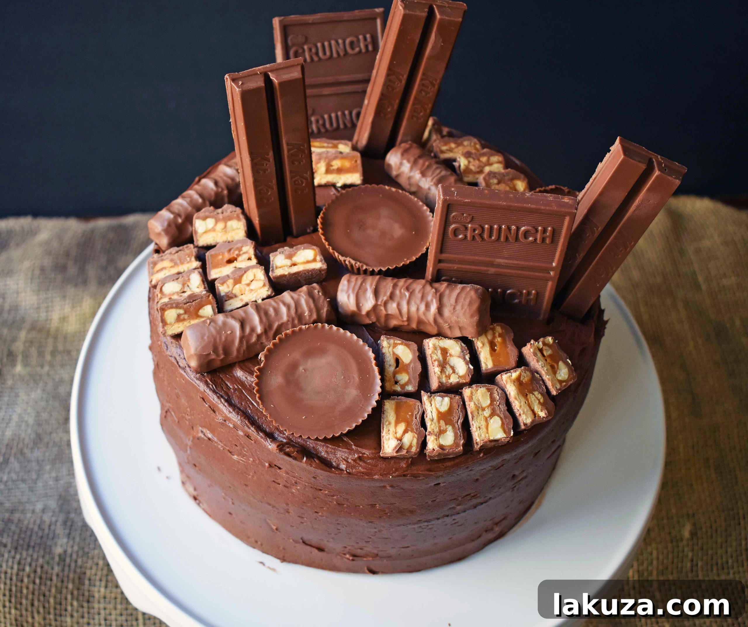Indulge in the ultimate Chocolate Candy Bar Cake from Modern Honey. Layers of tender, moist chocolate cake are generously frosted with perfect chocolate buttercream and decorated with a colorful array of favorite chocolate candy bars, promising a delightful texture and flavor explosion.