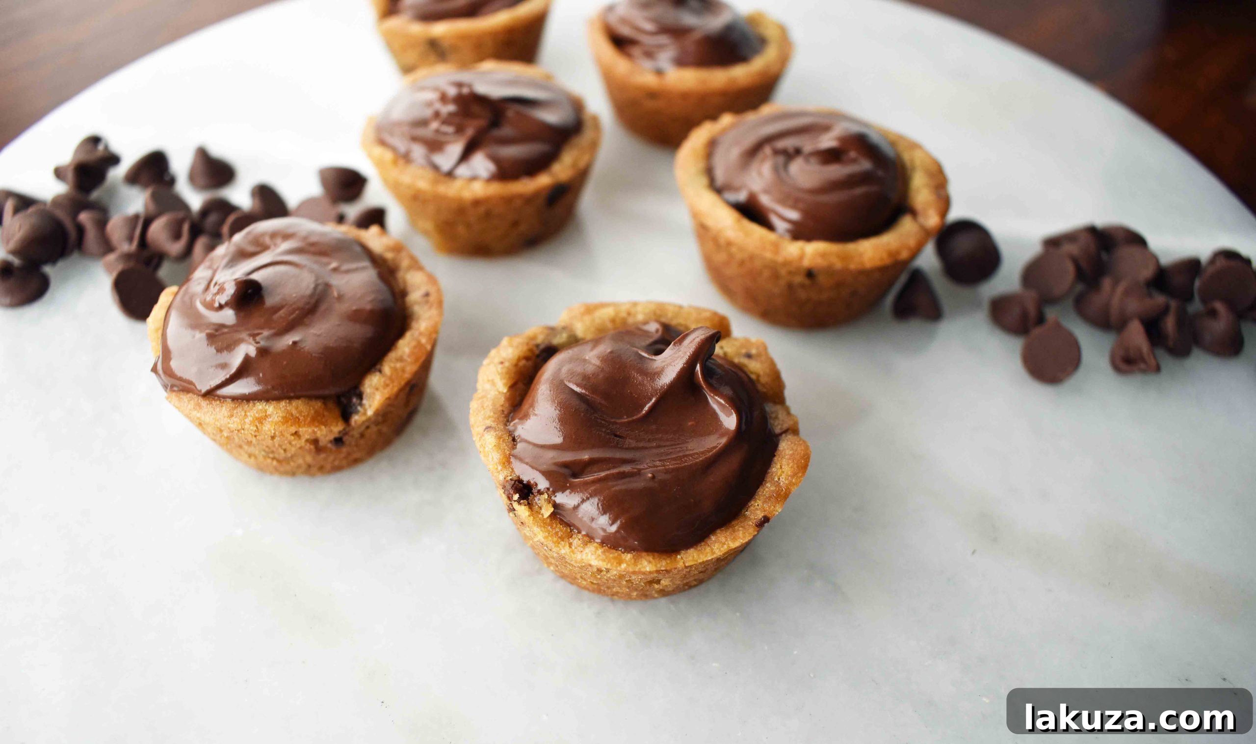 A pristine tray of freshly baked cookie cups, showcasing their consistent shape and readiness for a decadent ganache filling.