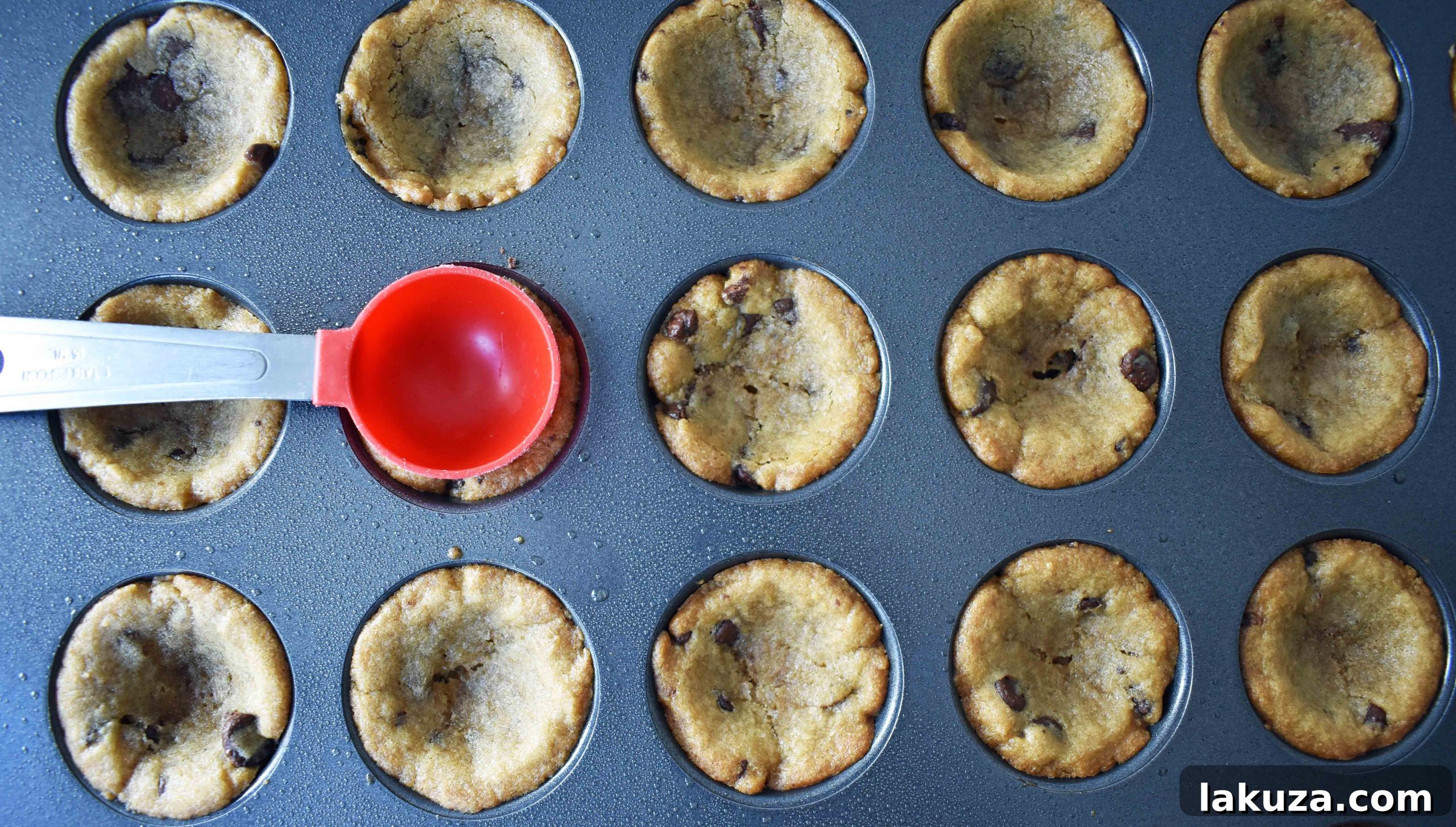 Technique for perfecting cookie cup wells: gently pressing the center with a spoon after baking, preparing them for ganache.