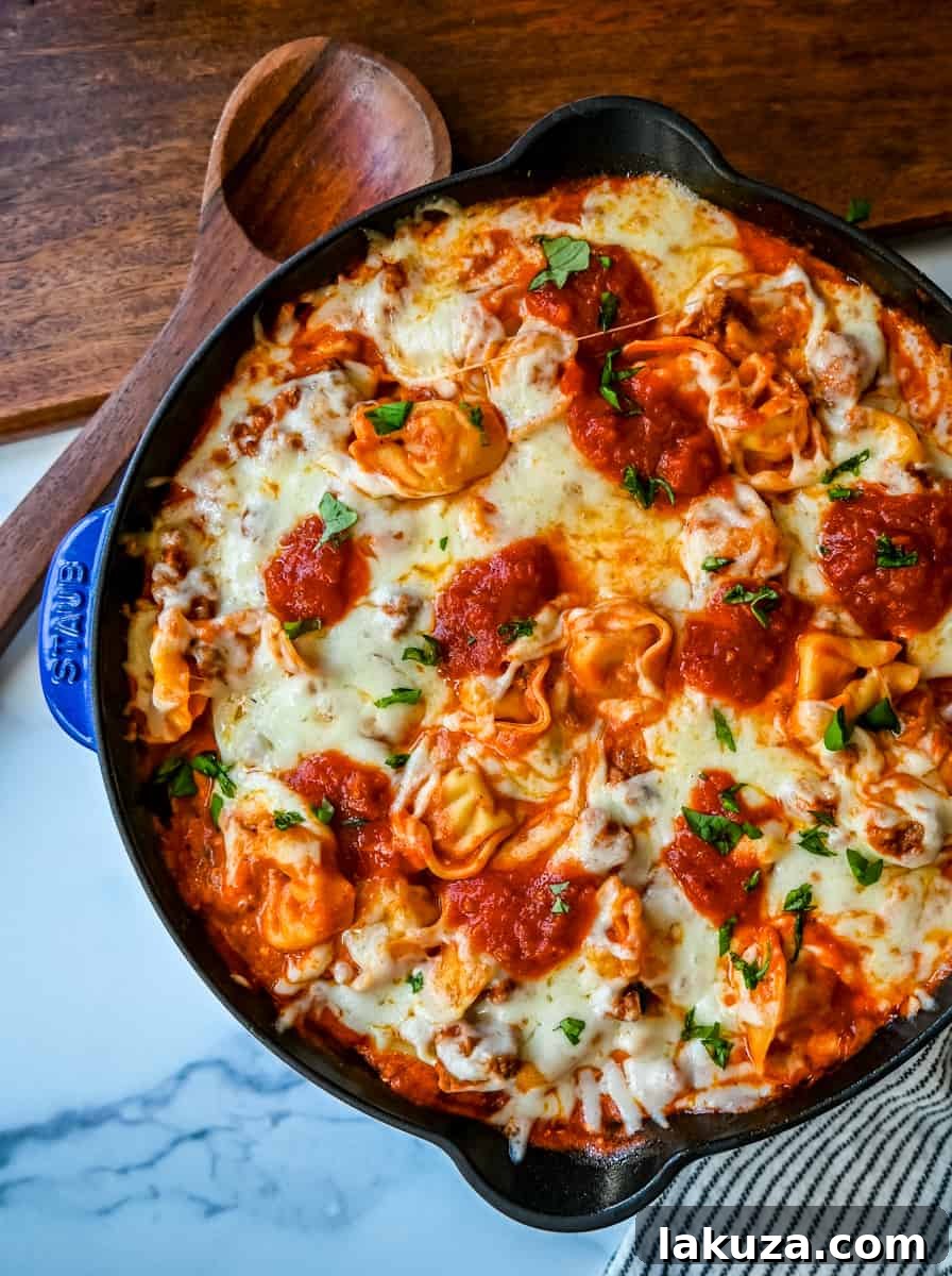 Pillowy Tortellini with Robust Sausage Ragu 3 Close-up of bubbling Cheese Tortellini with Sausage Ragu, highlighting the melted mozzarella and rich tomato sauce in a skillet, ready to serve.