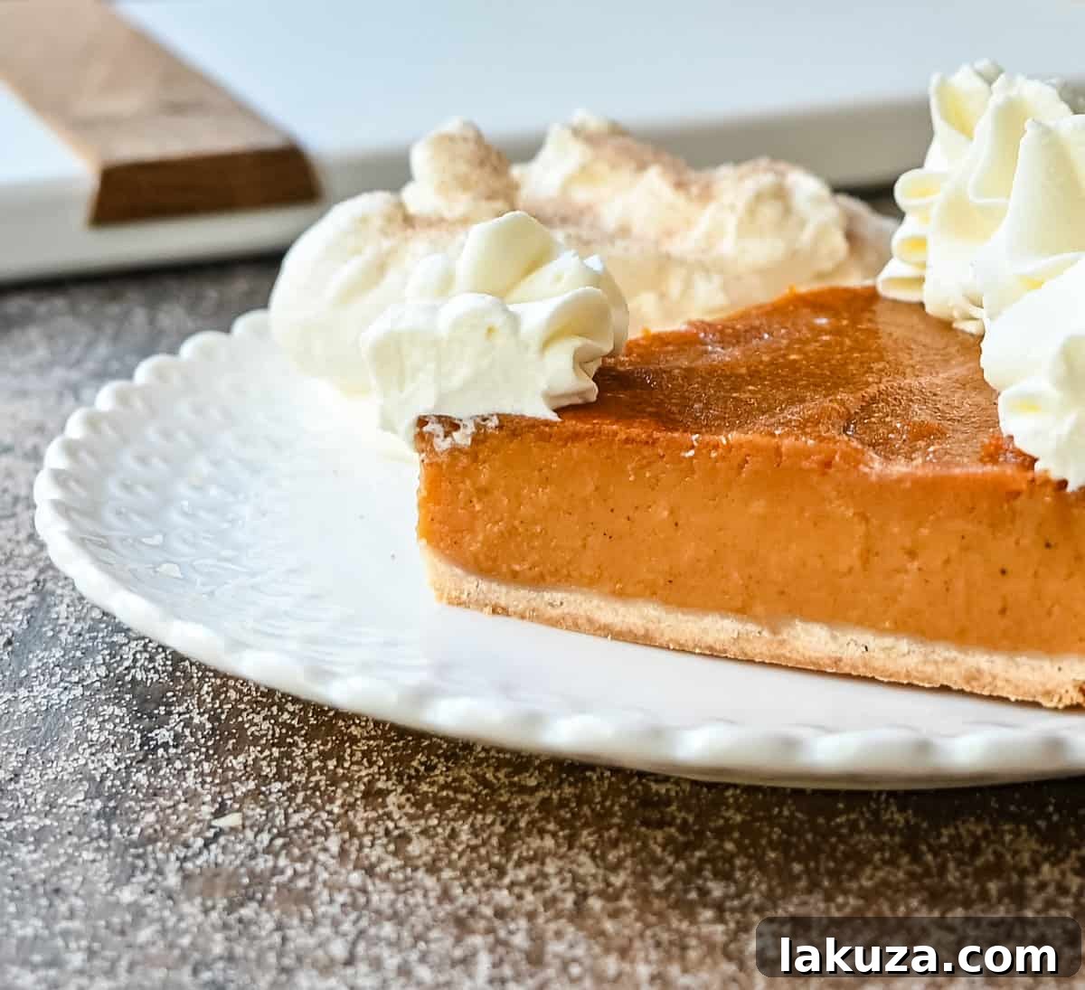 A perfect slice of Southern Sweet Potato Pie on a plate, topped with fresh whipped cream. The ideal Fall and Thanksgiving dessert.