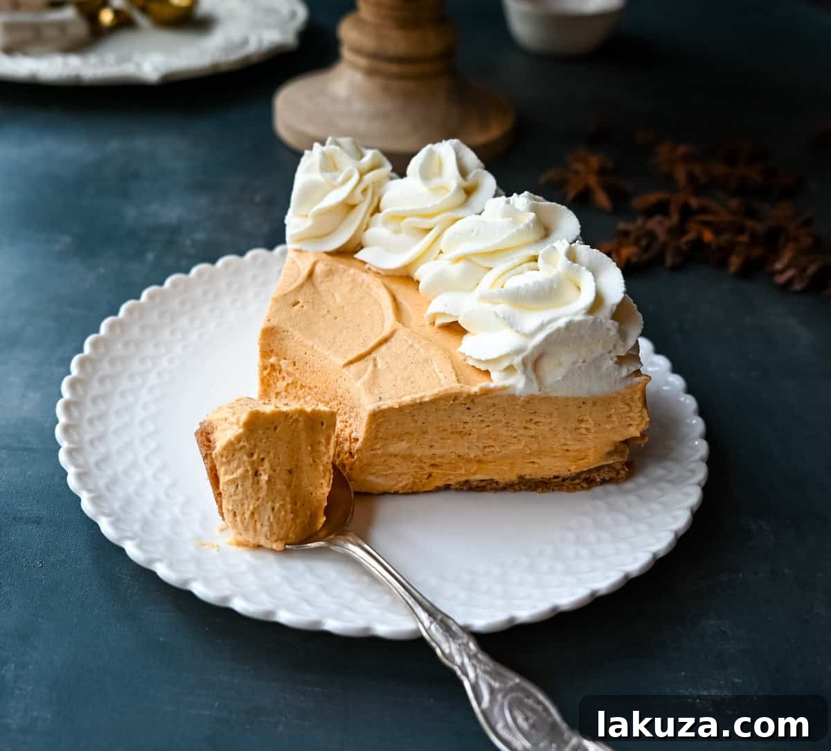 Effortless Pumpkin Cheesecake 3 Sliced No-Bake Pumpkin Cheesecake with whipped cream swirls, showcasing its creamy texture and graham cracker crust. Ideal for Fall gatherings.