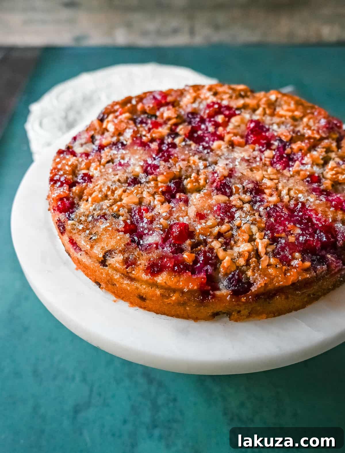 A slice of warm Nantucket Cranberry Pie with a dollop of fresh whipped cream, showcasing the vibrant cranberries and soft, golden-brown cake.