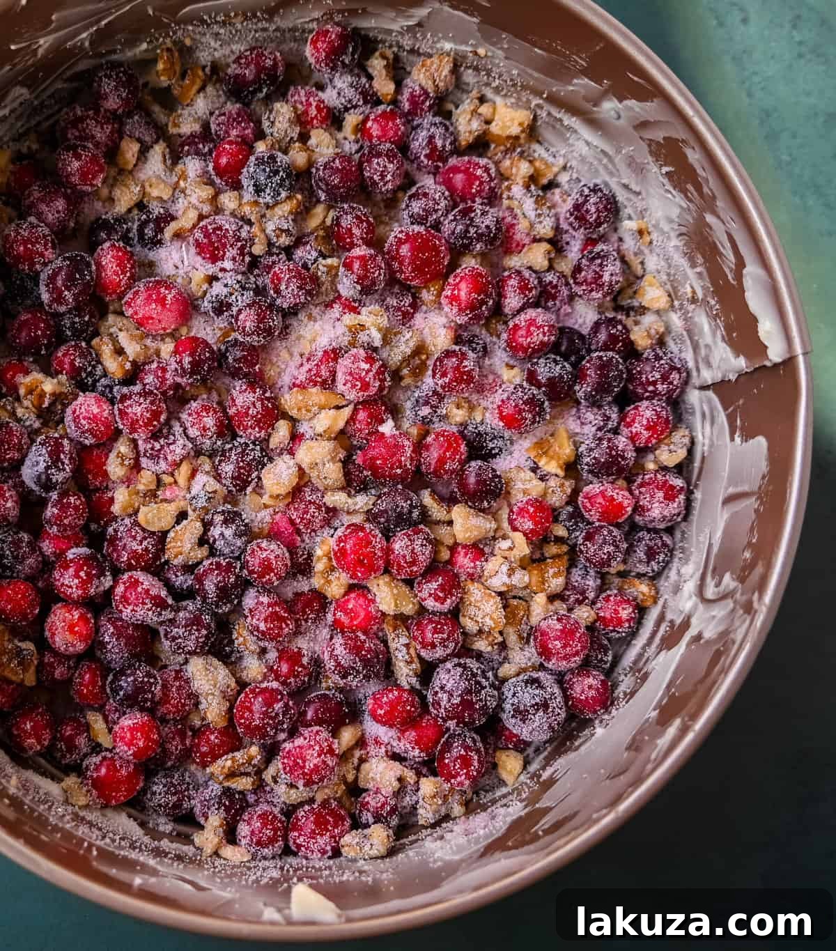 Close-up of fresh cranberries, sugar, and chopped nuts mixed together in a springform pan, forming the base of the Nantucket Cranberry Pie.