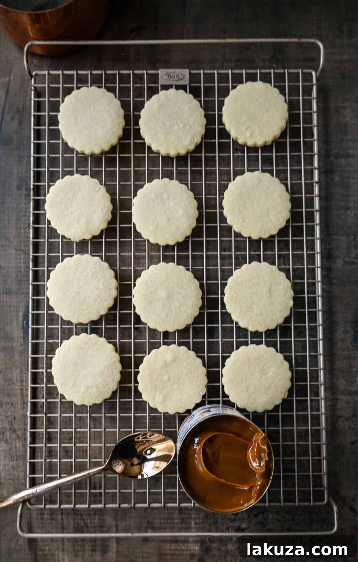 Cooked Alfajores cookies with dulce de leche being spread on one half.