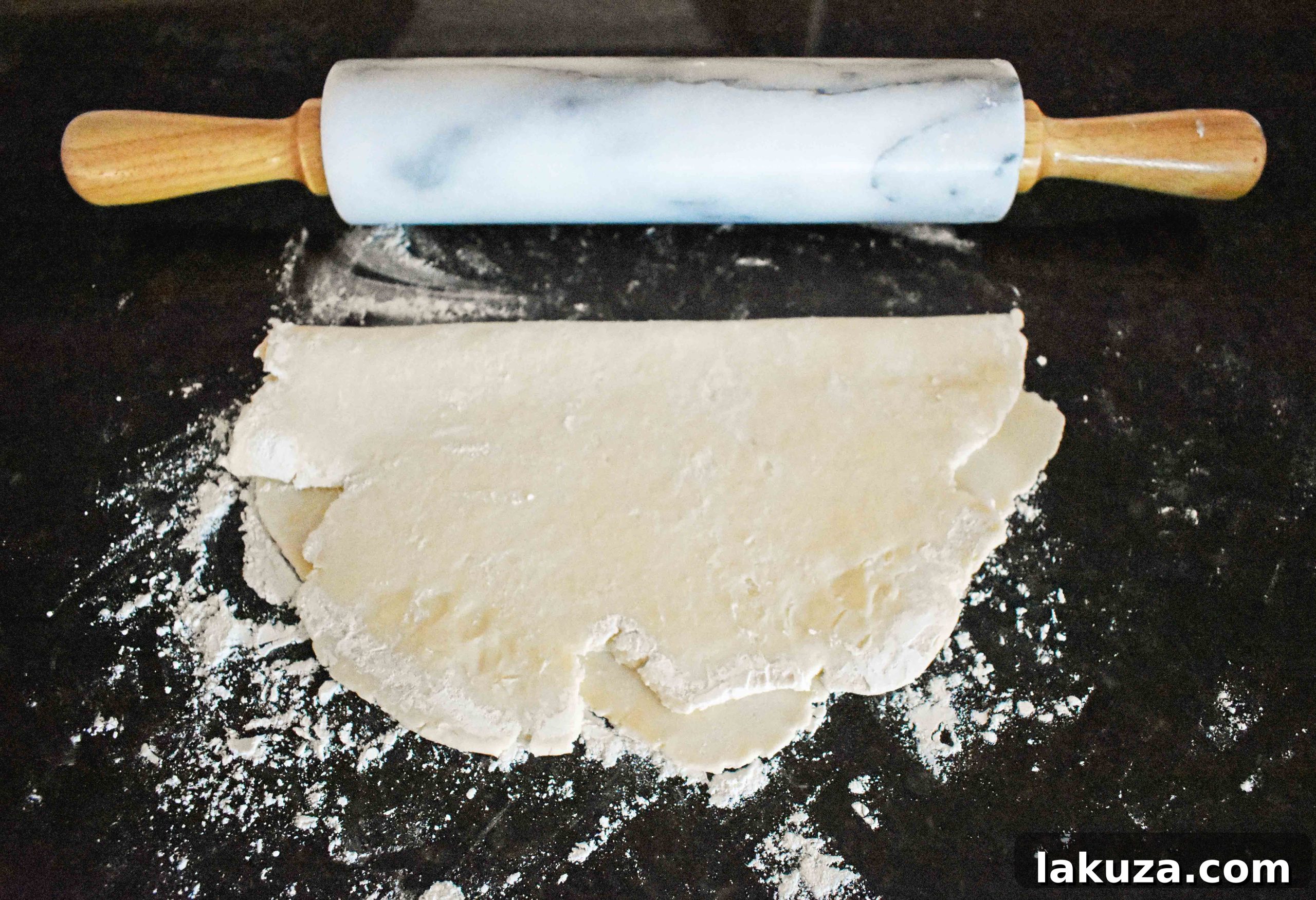 Rolling out pie dough on a lightly floured surface with a rolling pin
