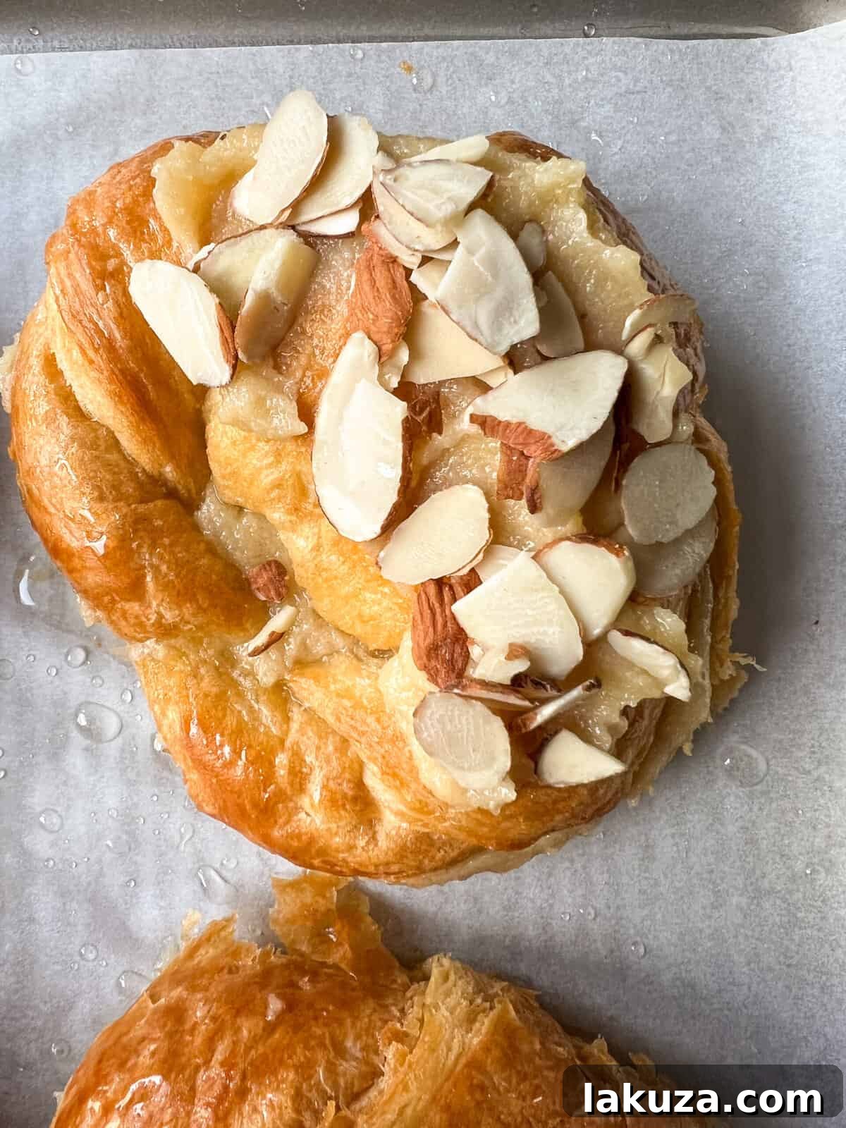 Close-up of a perfectly baked almond croissant, showcasing its golden crust and delicate powdered sugar dusting.