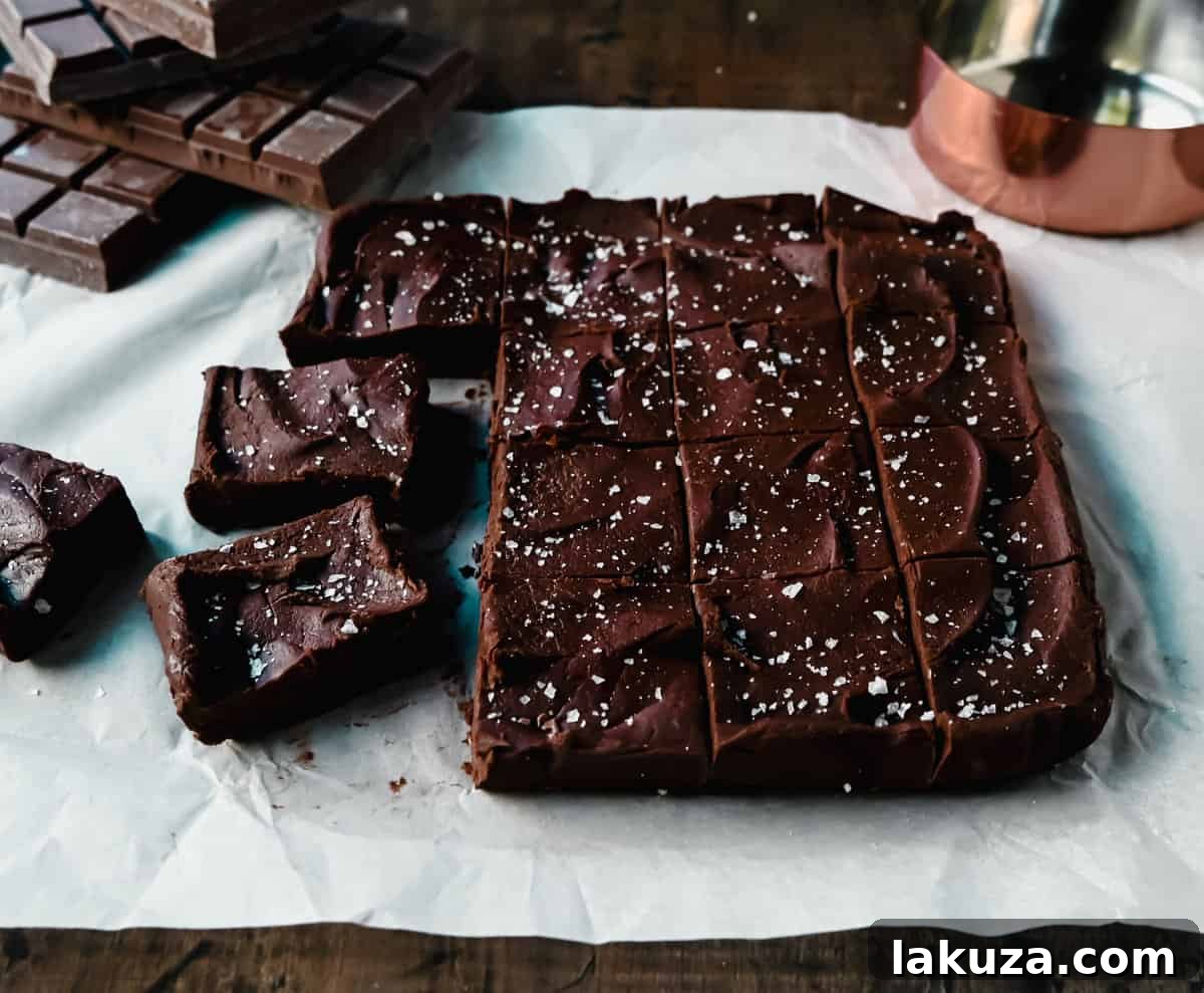 A slice of rich Easy 2-Ingredient Microwave Chocolate Fudge, highlighting its dense, smooth texture and perfect square shape, garnished with sea salt flakes.