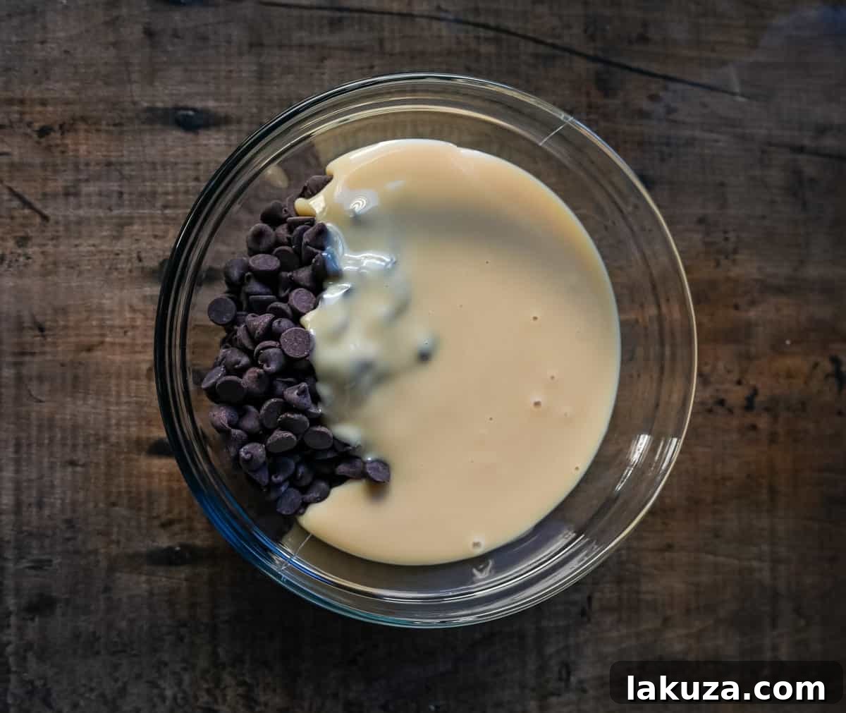 Chocolate chips and sweetened condensed milk are combined in a microwave-safe bowl, ready for melting into delicious fudge.
