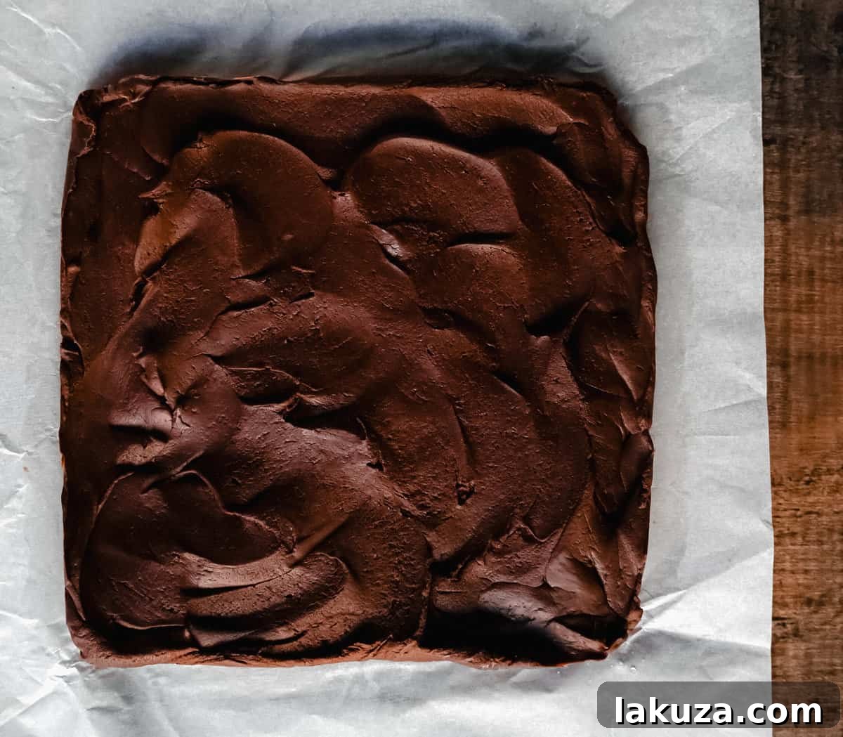 A beautifully presented block of Easy 2-Ingredient Microwave Chocolate Fudge, garnished with sea salt flakes, on a white cutting board.