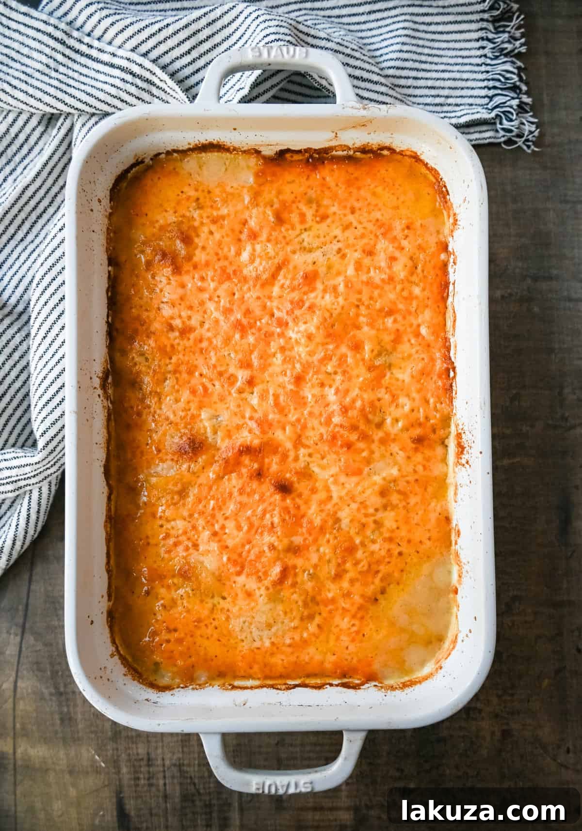 Close-up of layers of thinly sliced Yukon Gold potatoes smothered in a rich, creamy cheese sauce, ready for baking.