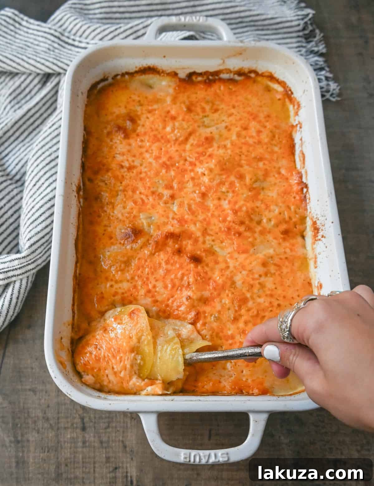 A close-up shot of golden, bubbly cheesy scalloped potatoes in a white baking dish, fresh from the oven.
