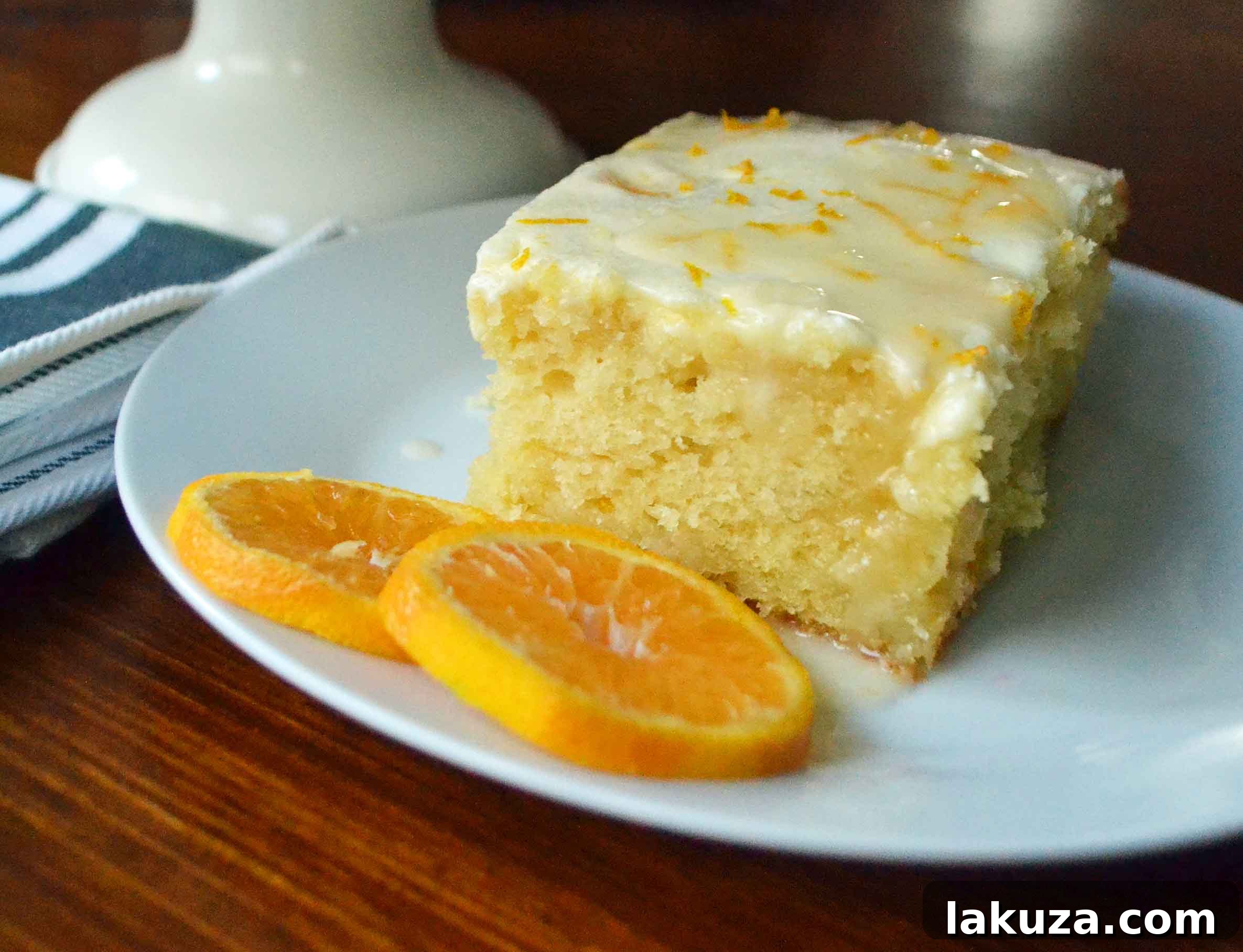 Close-up of a slice of Orange Roll Breakfast Cake, showcasing its moist texture, buttery orange swirls, and luscious cream cheese glaze.