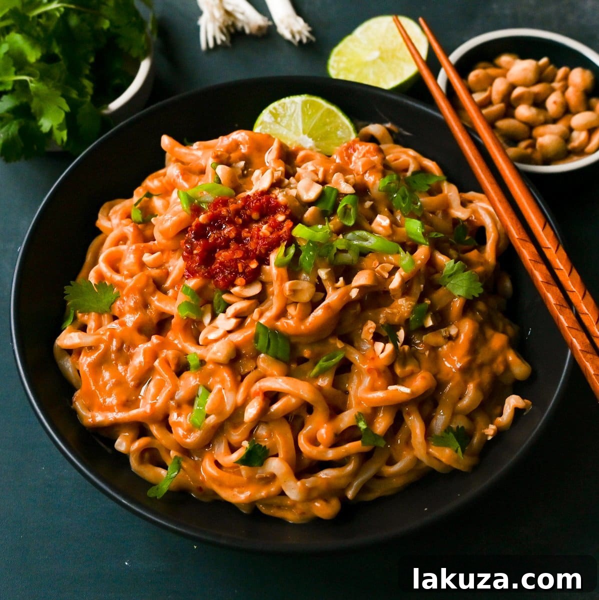 Creamy Chili Peanut Noodles 2 A vibrant bowl of Spicy Peanut Noodles, garnished with fresh cilantro, green onions, and chopped peanuts, ready to be enjoyed. These easy peanut noodles are made in less than 15 minutes.