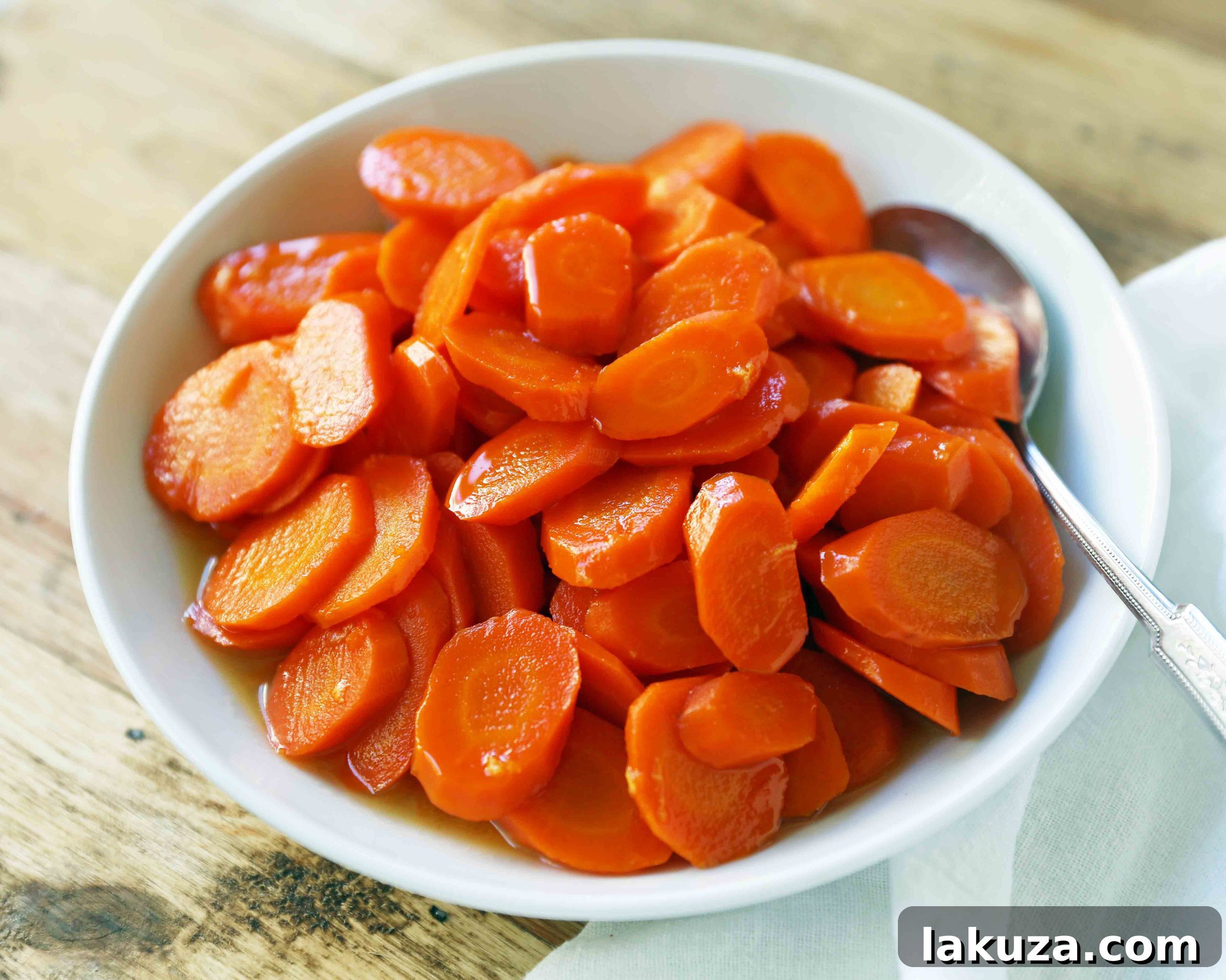 Close-up of golden honey butter glazed carrots on a plate with fresh herbs