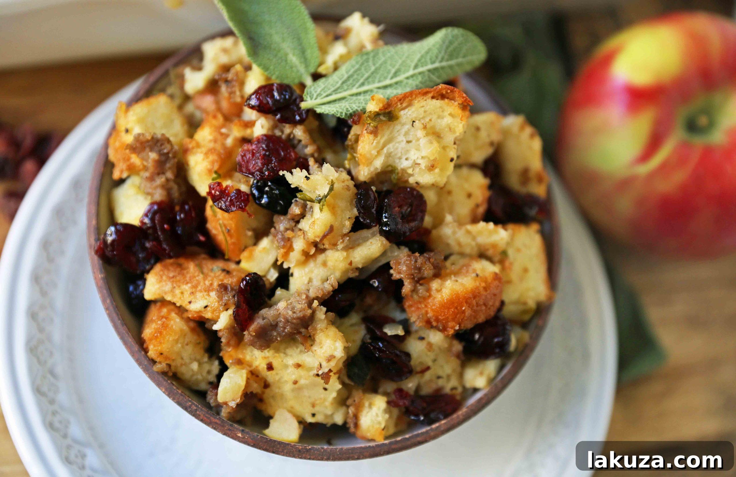 Close-up of Cranberry Apple Sausage Stuffing in a baking dish, showcasing the texture of bread cubes, sausage, apples, and cranberries.