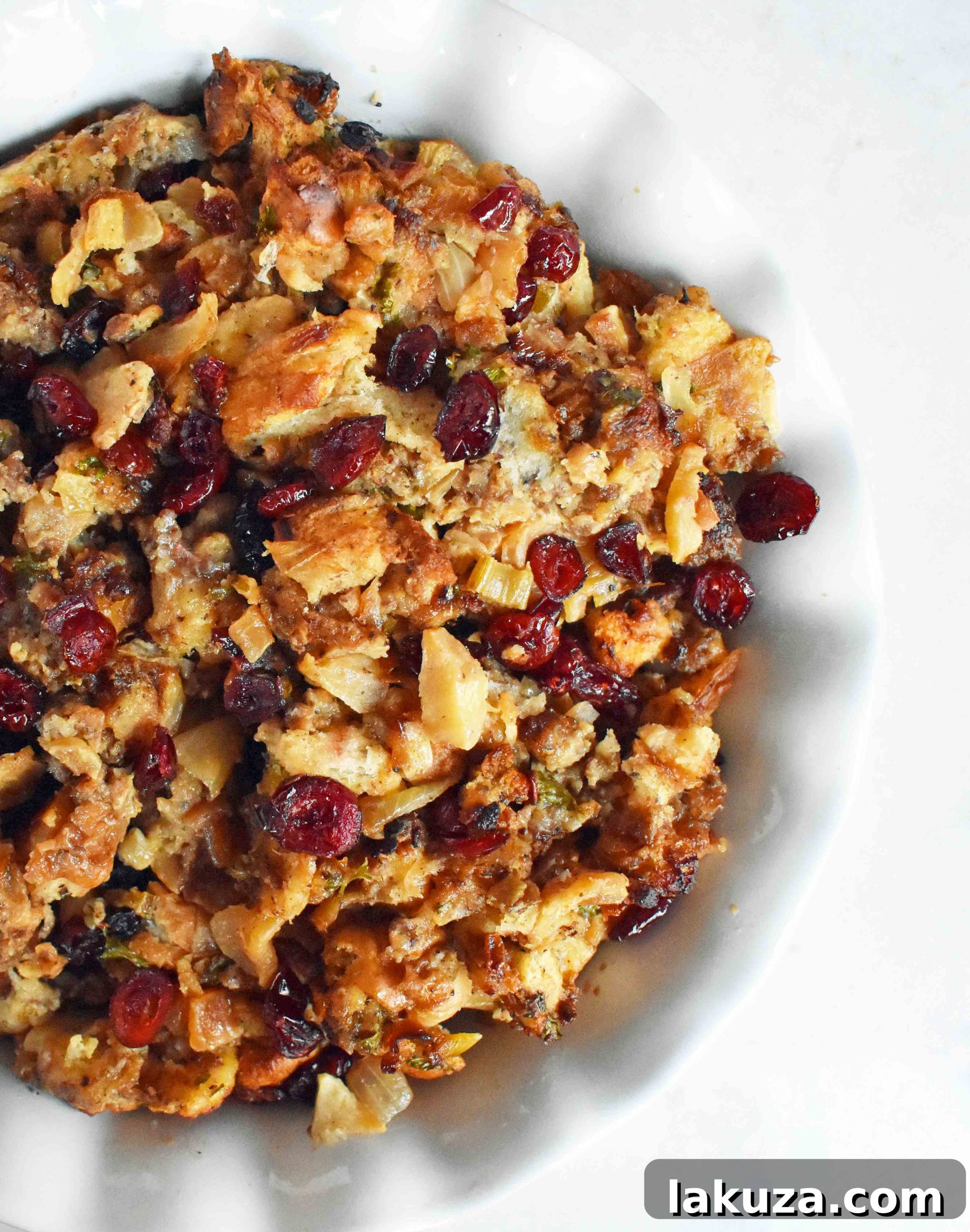 Overhead shot of Cranberry Apple Sausage Stuffing with a spoon, highlighting the golden crust.