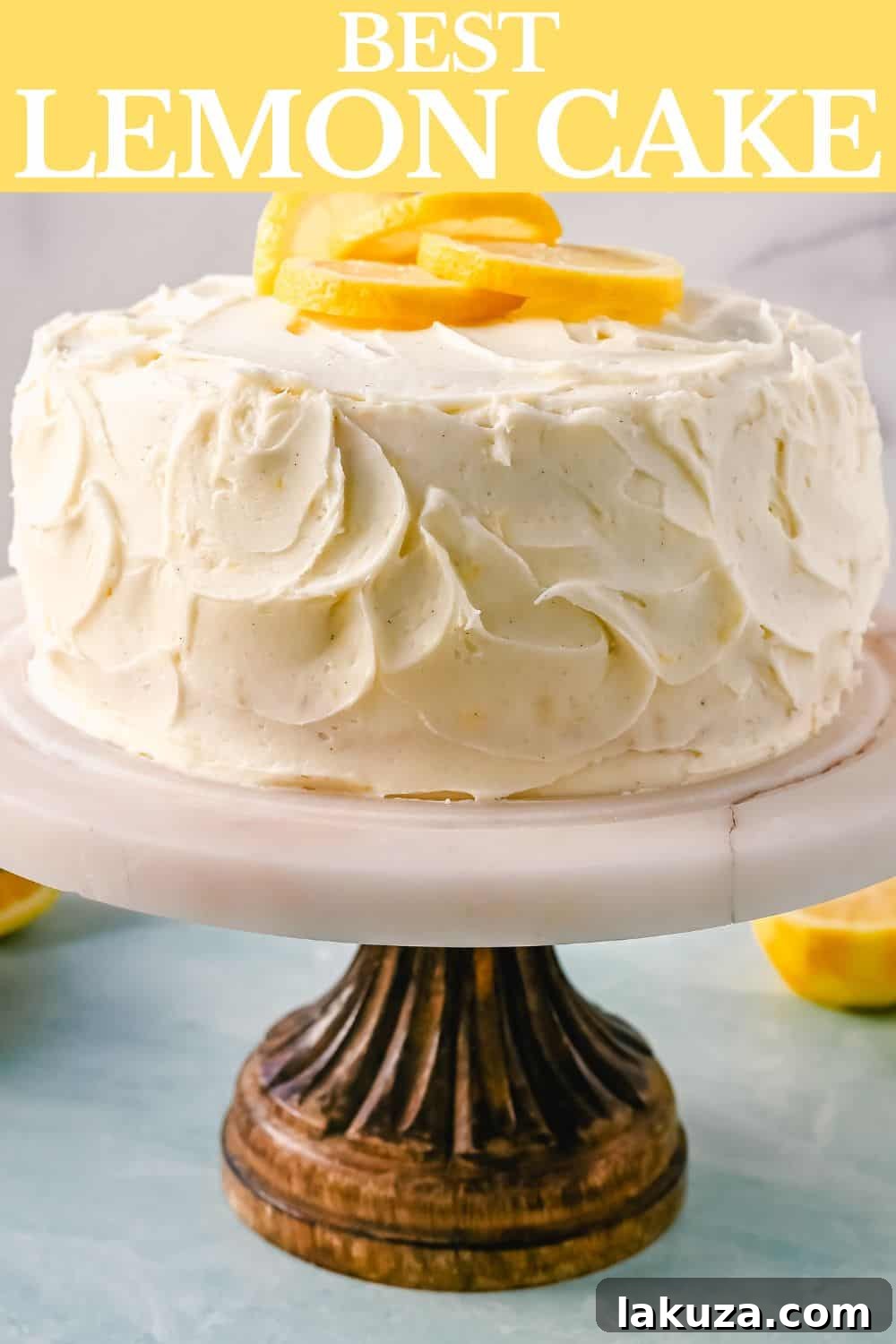 A tall, elegant Lemon Layer Cake with visible layers of moist cake, tangy lemon curd, and generous lemon cream cheese frosting, garnished with fresh lemon.