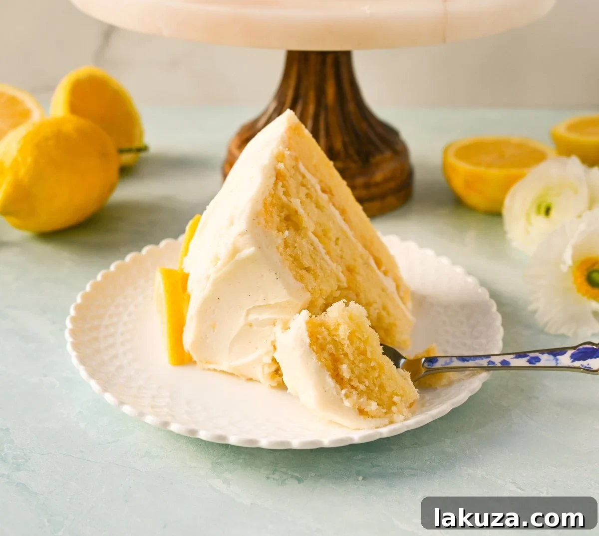 Close-up of a slice of the Best Lemon Cake Recipe, showcasing its moist layers, lemon curd, and fluffy lemon cream cheese frosting.