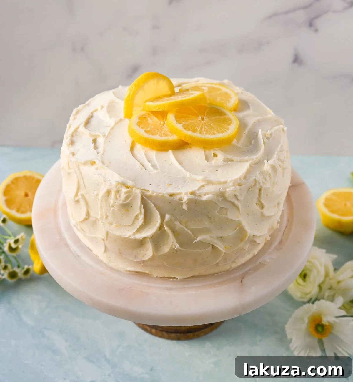 Close-up of a generously frosted slice of the Best Lemon Layer Cake, featuring the creamy lemon cream cheese frosting and visible lemon zest.