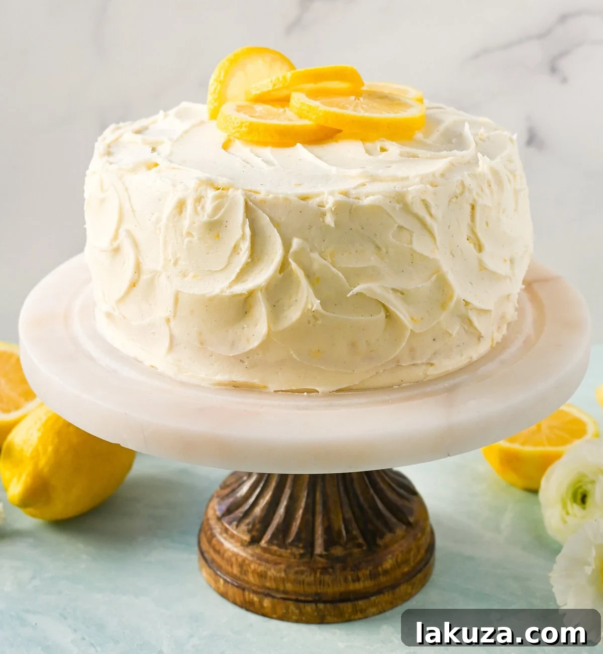 A stunning side view of the Best Lemon Cake Recipe, showcasing perfectly stacked layers of cake, lemon curd, and fluffy lemon cream cheese frosting.