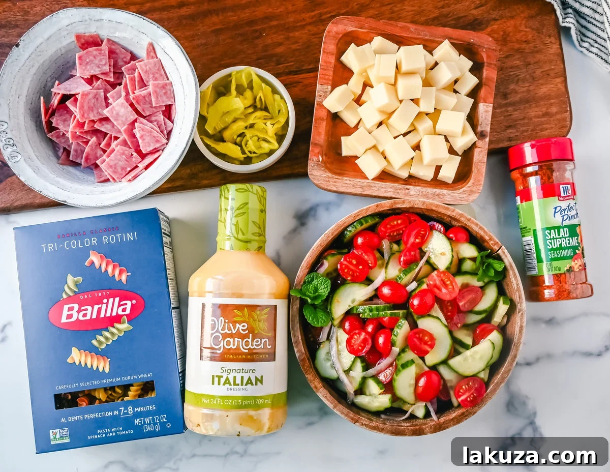 A close-up of fresh ingredients for an Easy Pasta Salad, showcasing pasta, grape tomatoes, cucumber, red onion, cubed cheese, and salami, alongside Olive Garden dressing and Salad Supreme Seasoning.