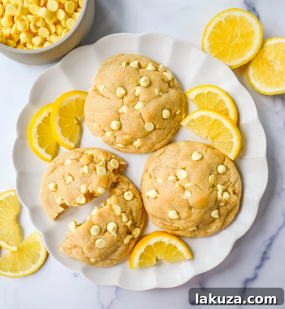 Three freshly baked Levain Bakery Lemon Cookies arranged on a marble surface, showing off their golden-brown edges and soft centers.
