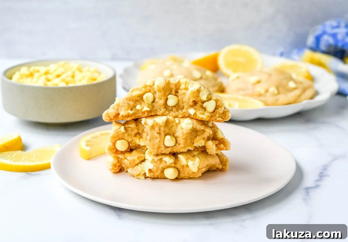 Three freshly baked, thick Levain Bakery Lemon Cookies cooling on a wire rack, steam gently rising.