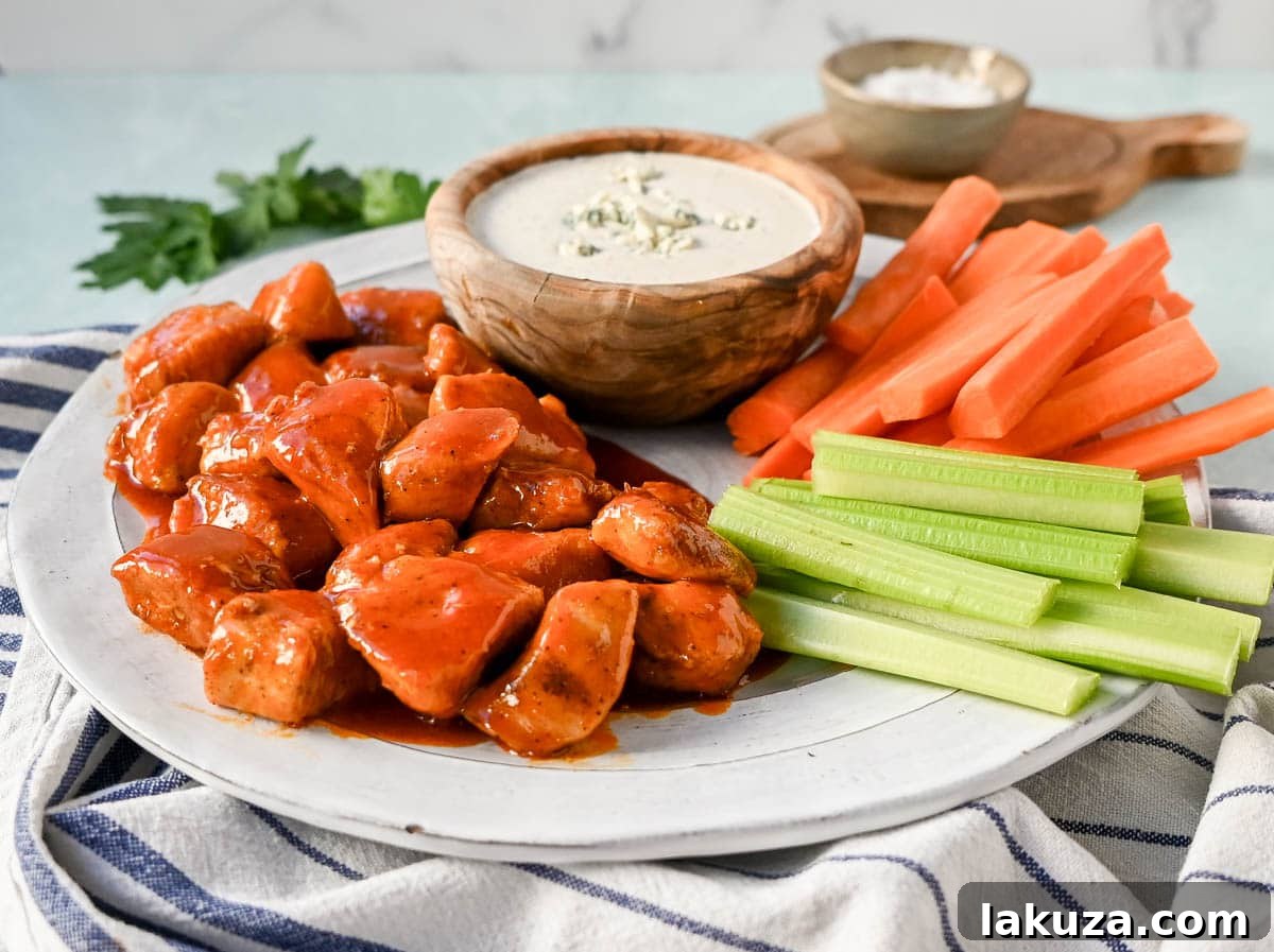 Close-up of skillet-cooked Buffalo Chicken Bites, glistening with rich, tangy sauce, ready to be served. A perfect healthy appetizer or meal.