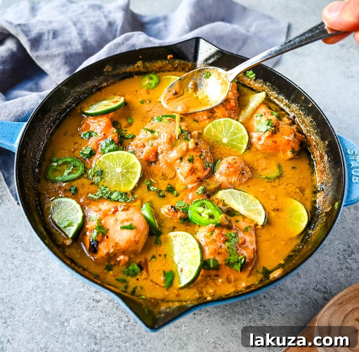 Island Zest Coconut Lime Chicken 4 A skillet full of cooked Coconut Lime Chicken, garnished with fresh lime slices and cilantro.