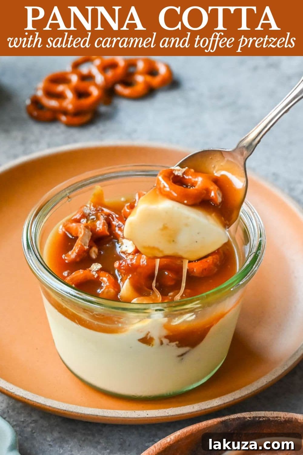 A beautifully presented vanilla panna cotta, topped with shimmering salted caramel and a sprinkle of golden toffee pretzels, ready to be enjoyed.