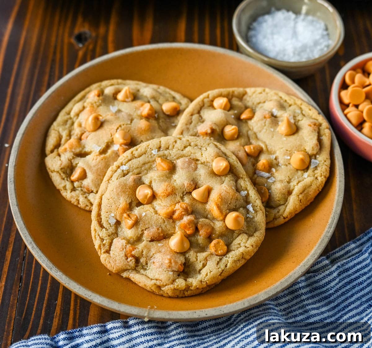 Golden-brown butterscotch chip cookies with melted butterscotch chips on a white background, highlighting their soft centers and crispy edges.