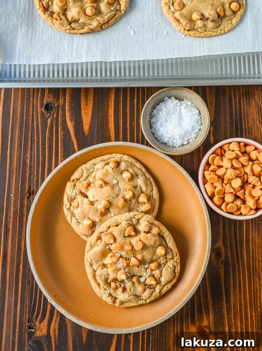 A close-up of a stack of warm butterscotch chip cookies, showcasing their chewy texture and abundance of butterscotch chips.