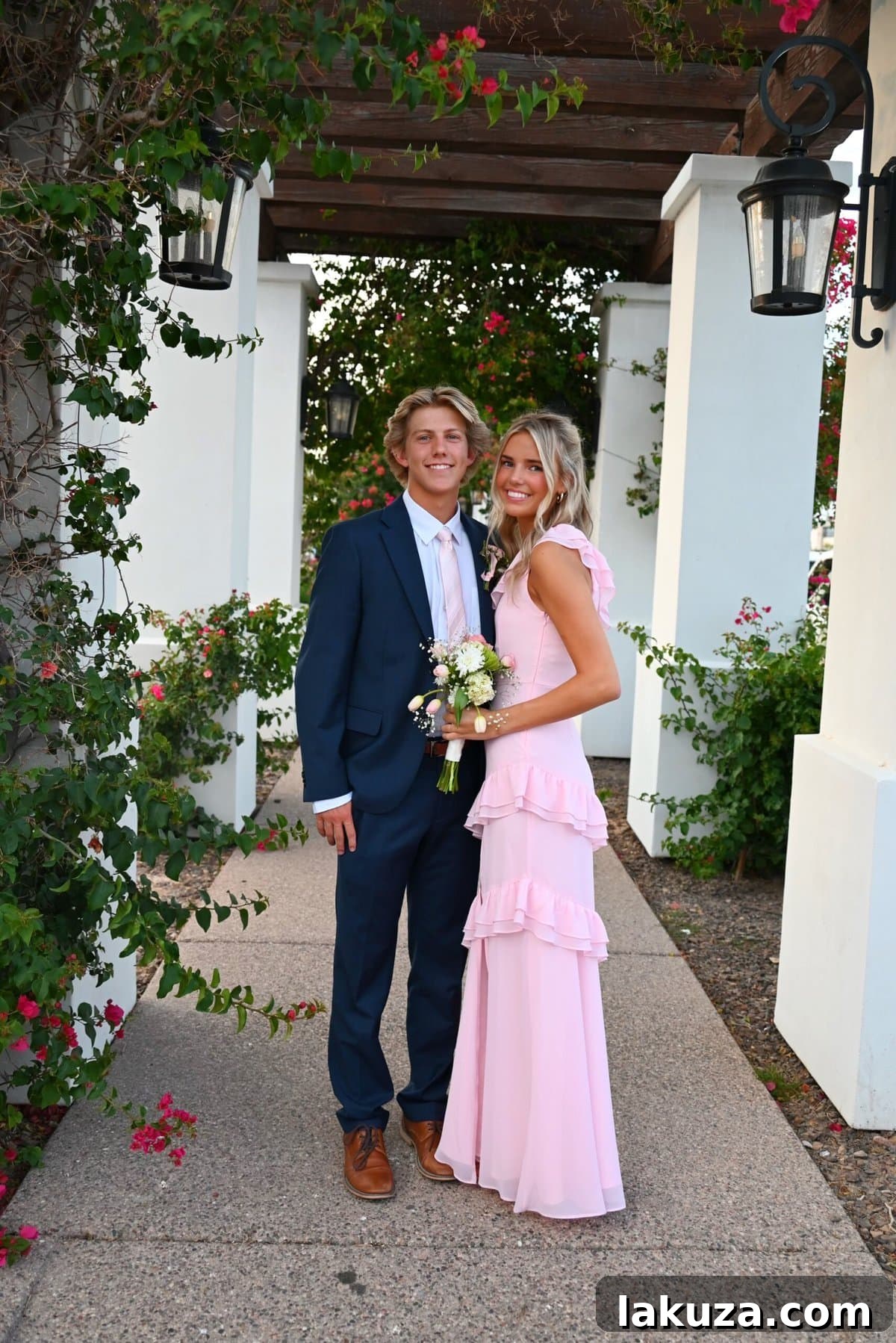 A young couple, dressed for prom, smiling brightly. The boy wears a tuxedo, and the girl wears an elegant dress.
