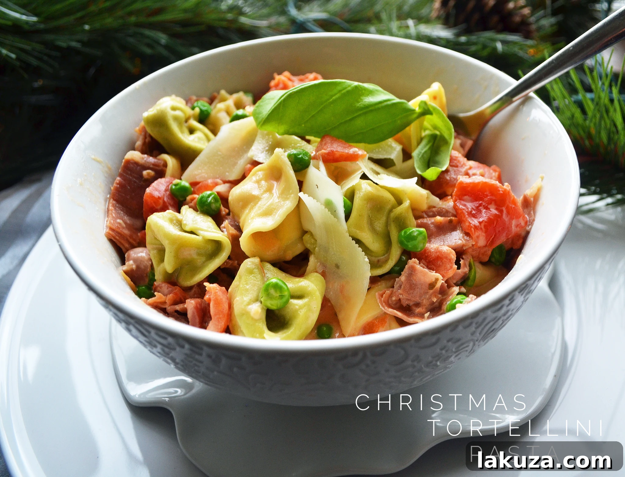 Overhead shot of a large platter of Tortellini Pasta with Prosciutto and Peas, garnished with fresh herbs.